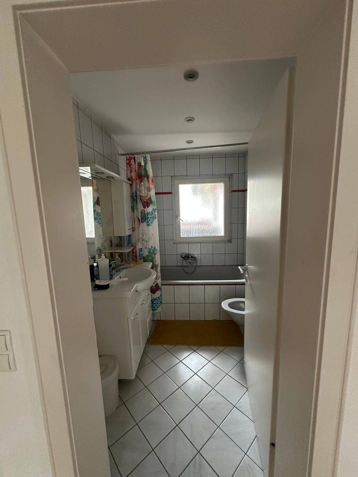 Badezimmer mit Badewanne, WC, Waschbecken und bunten Duschvorhang.