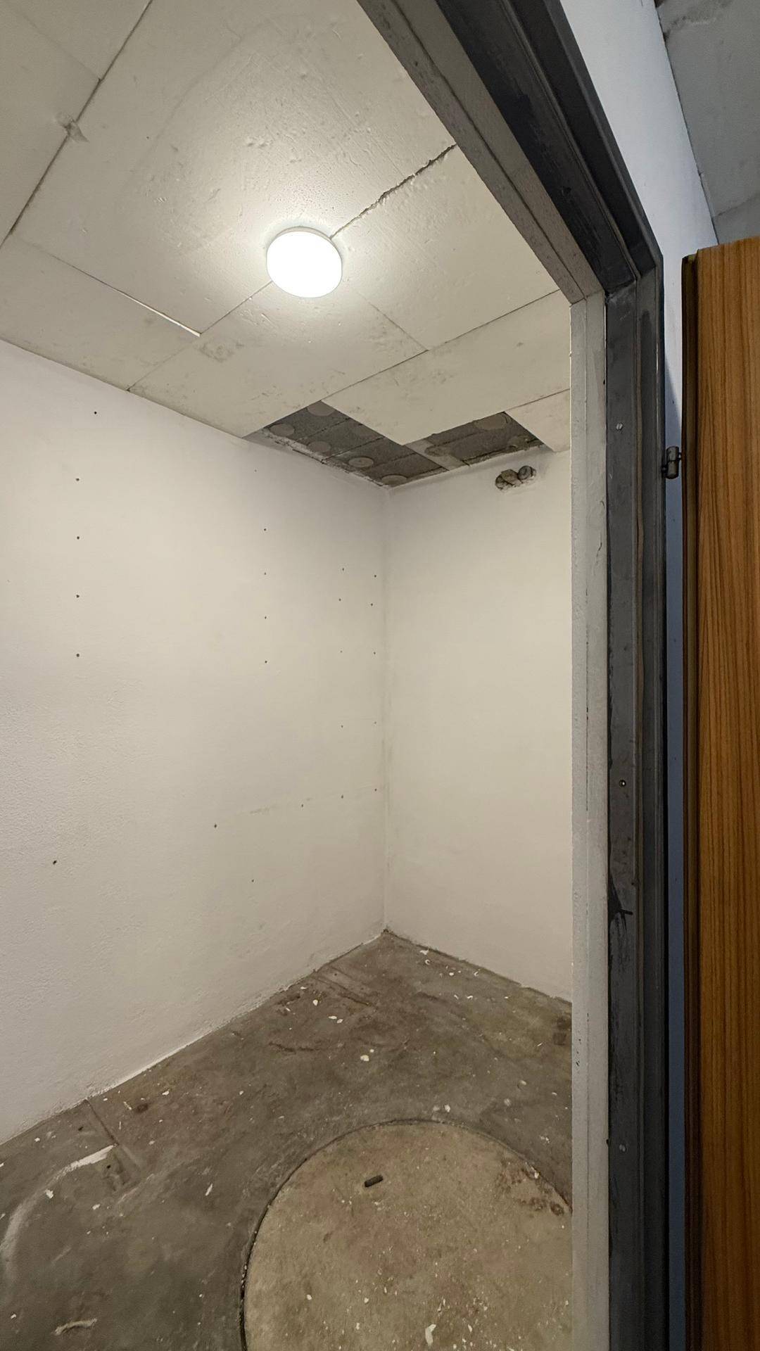 Kleiner, unfertiger Abstellraum im Keller mit Betonboden und einfacher Deckenbeleuchtung.