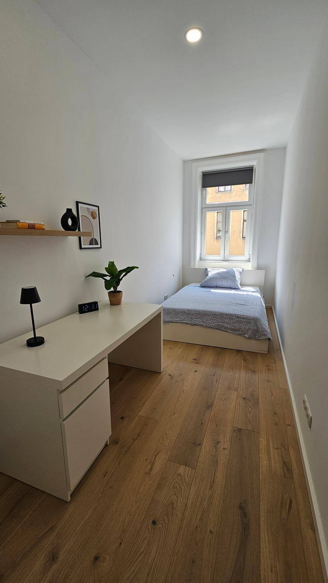 Gemütliches Schlafzimmer mit Einzelbett, Schreibtisch und Fenster für natürliches Licht.