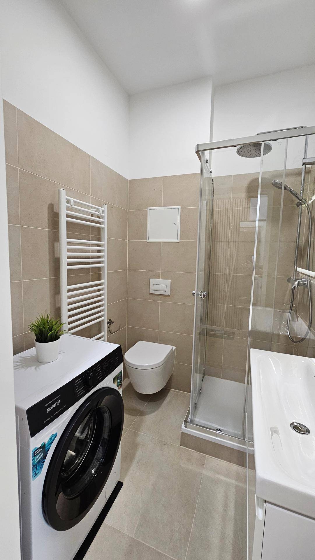 Modernes Badezimmer mit Duschkabine, WC, Waschbecken und beheiztem Handtuchhalter.