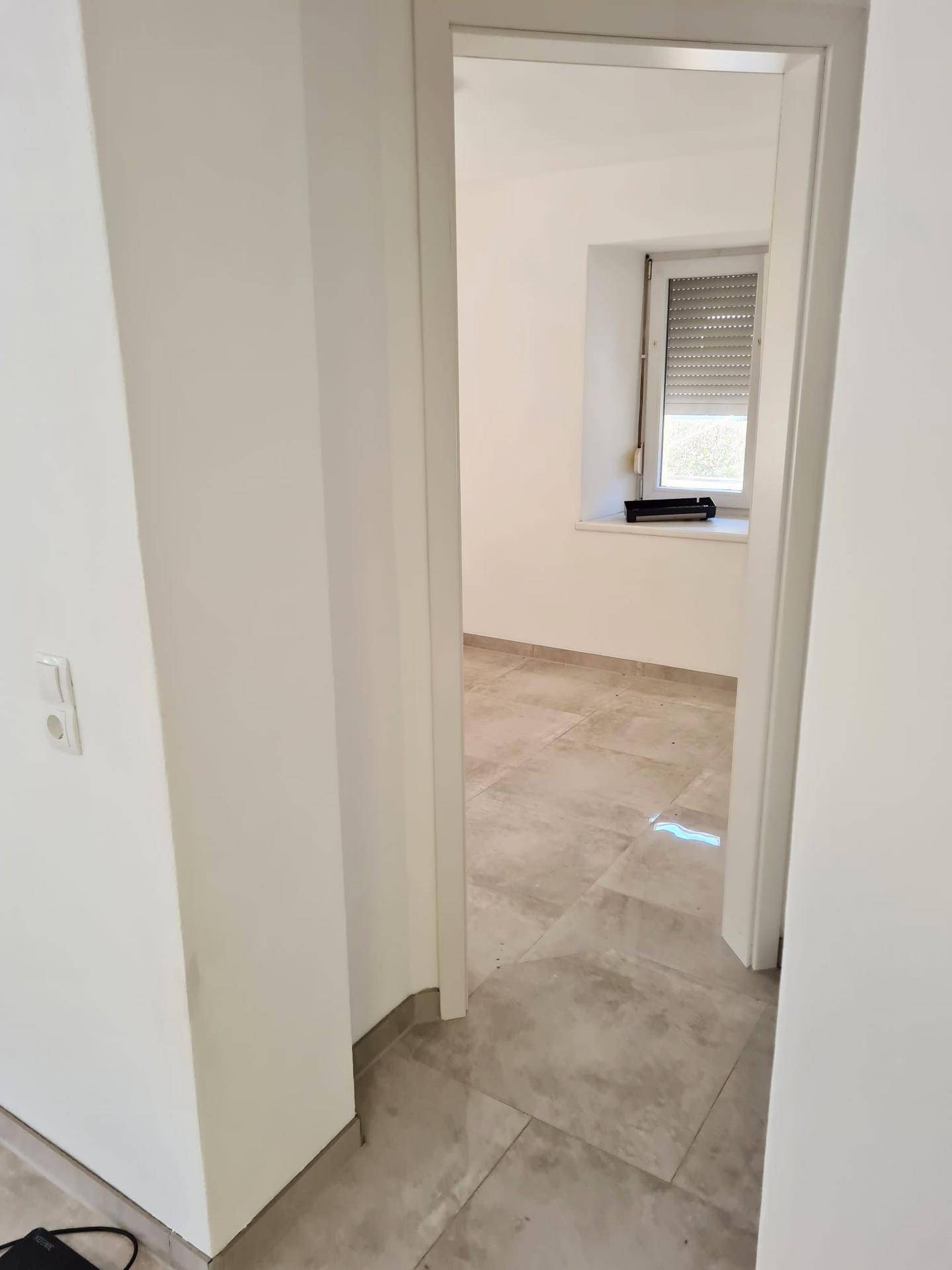 Heller Flur mit Fliesenboden, der den Zugang zu einem weiteren Zimmer der Wohnung ermöglicht.