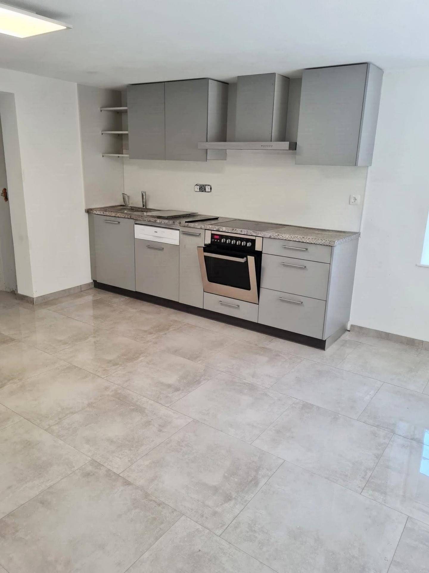 Moderne Einbauküche in Grau mit integrierten Geräten, Kochfeld und Dunstabzugshaube.
