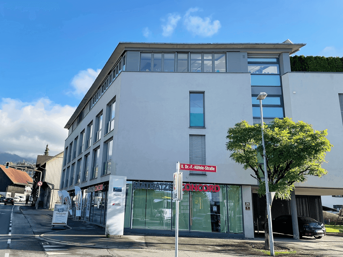 Moderne Architektur des Gebäudes mit klaren Linien und großen Fensterfronten an einer Straße.
