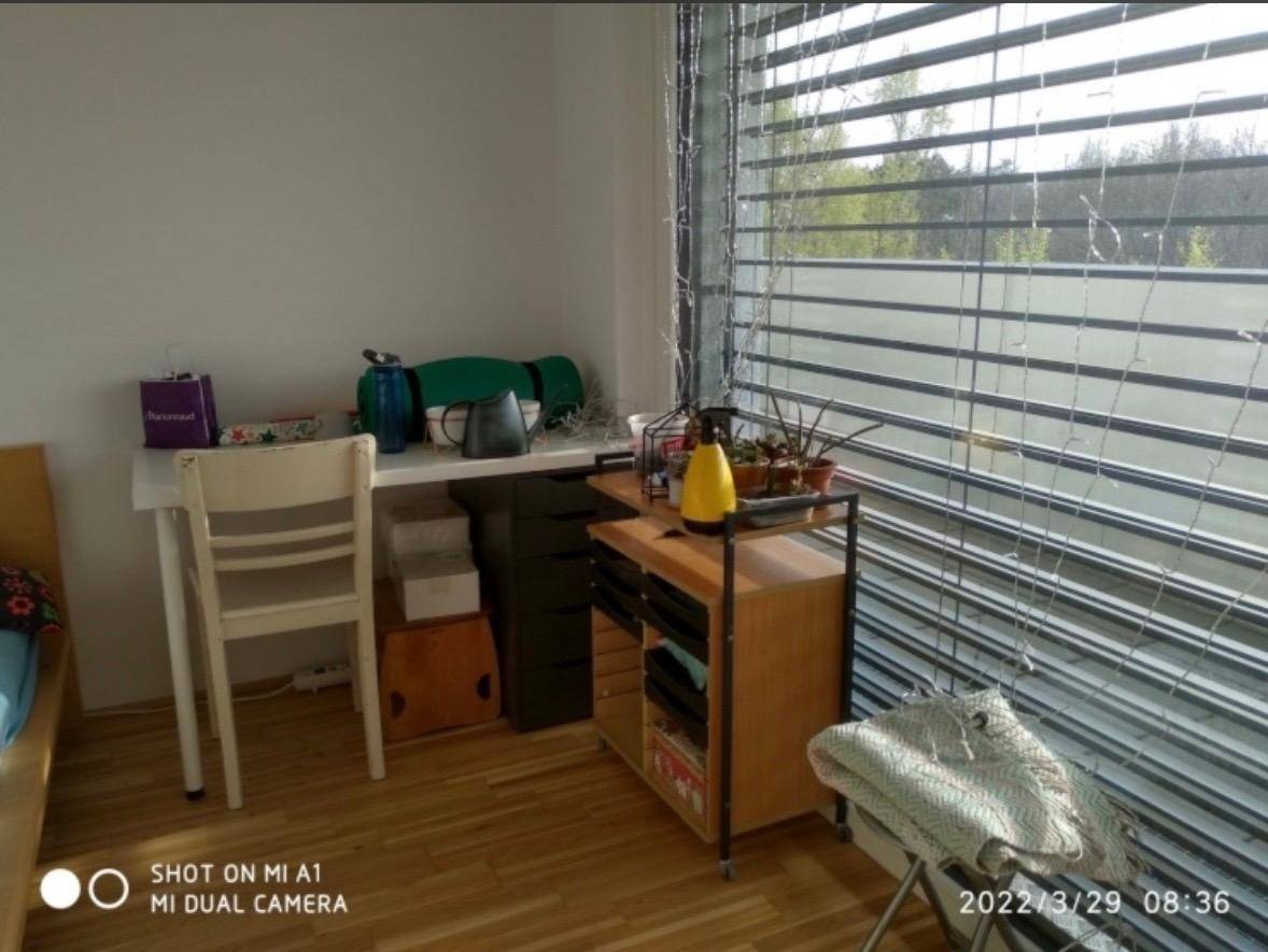 Arbeitsbereich im Schlafzimmer mit Schreibtisch, Stuhl und großem Fenster mit Jalousien.