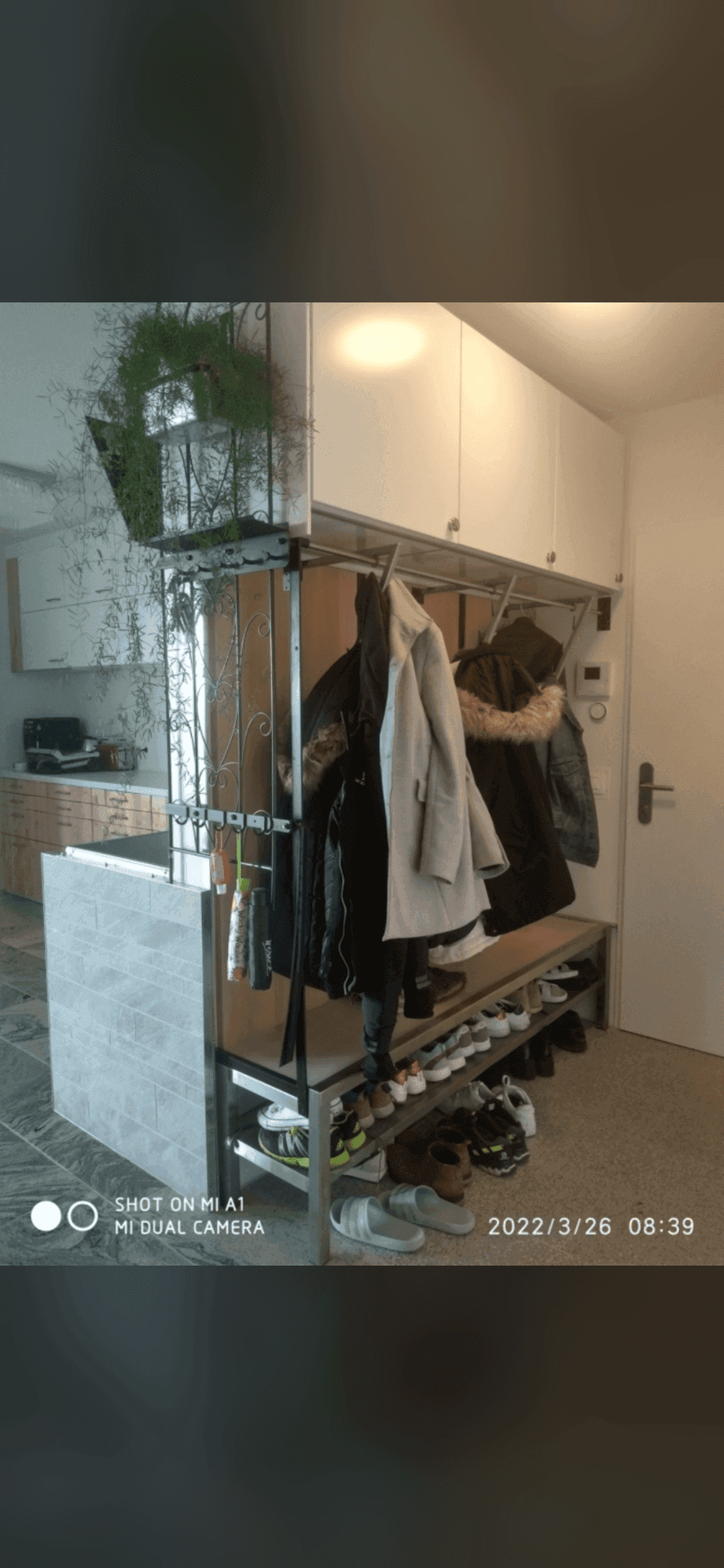 Eingangsbereich mit Garderobe, Schuhregal und Blick in die angrenzende Küche.