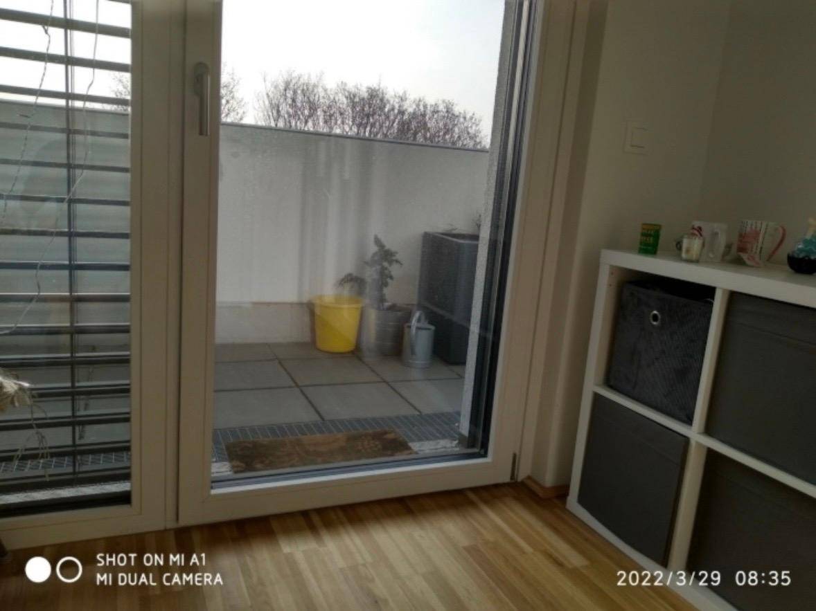 Große Terrassentür führt zu einem gefliesten Außenbereich mit gelbem Eimer.