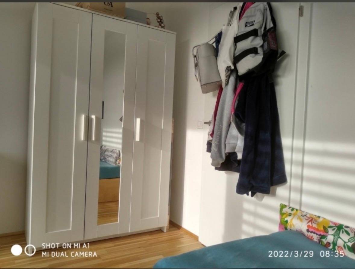 Weißer Kleiderschrank mit Spiegeltüren im Schlafzimmer, bietet viel Stauraum.