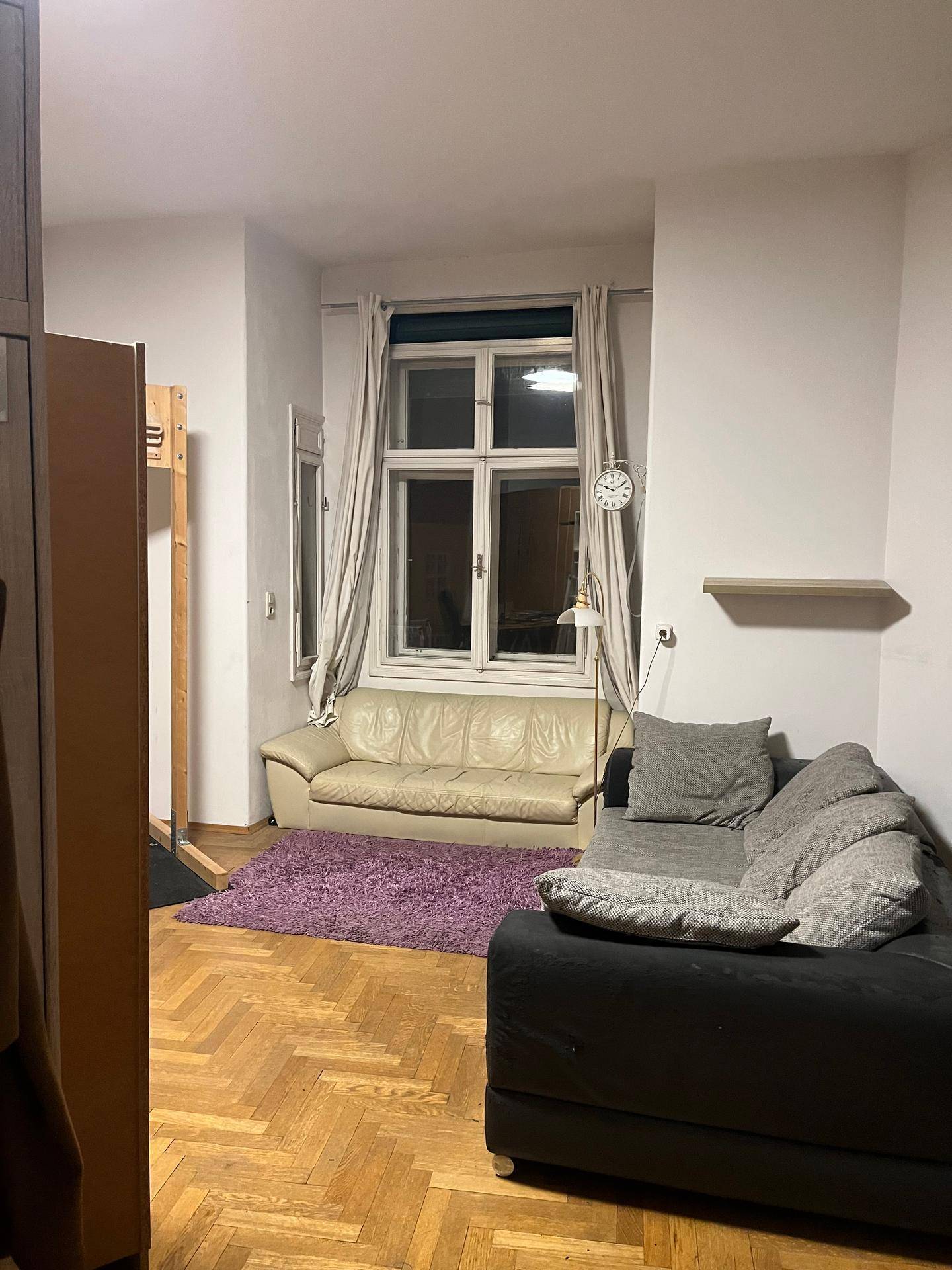 Wohnbereich mit zwei Sofas, einem lila Teppich und einem Fenster.