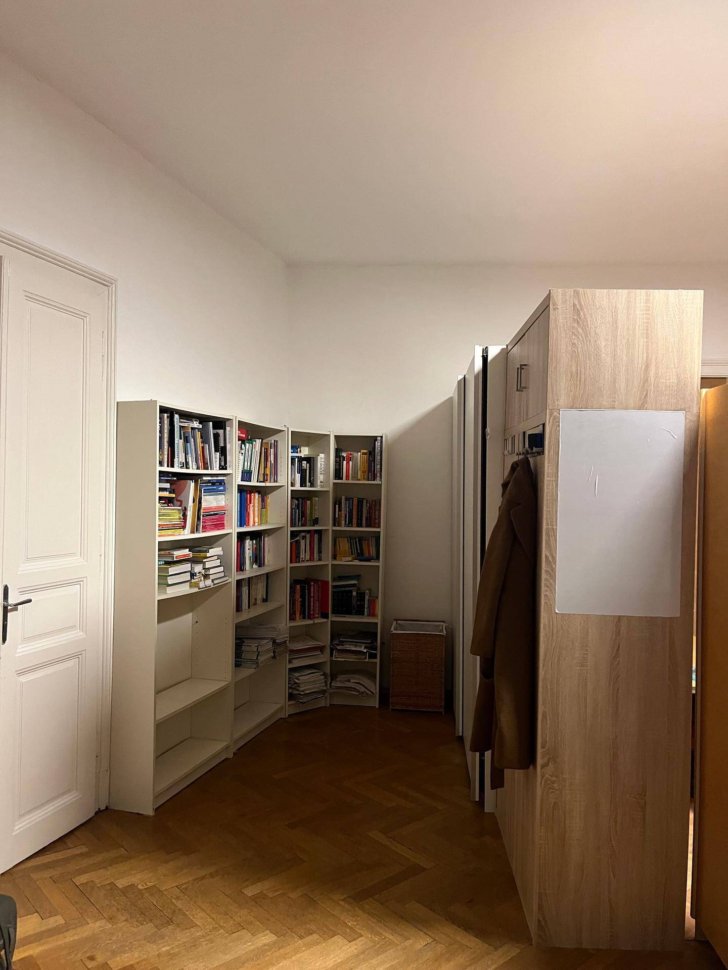 Flurbereich mit mehreren Bücherregalen, Garderobe und Parkettboden.