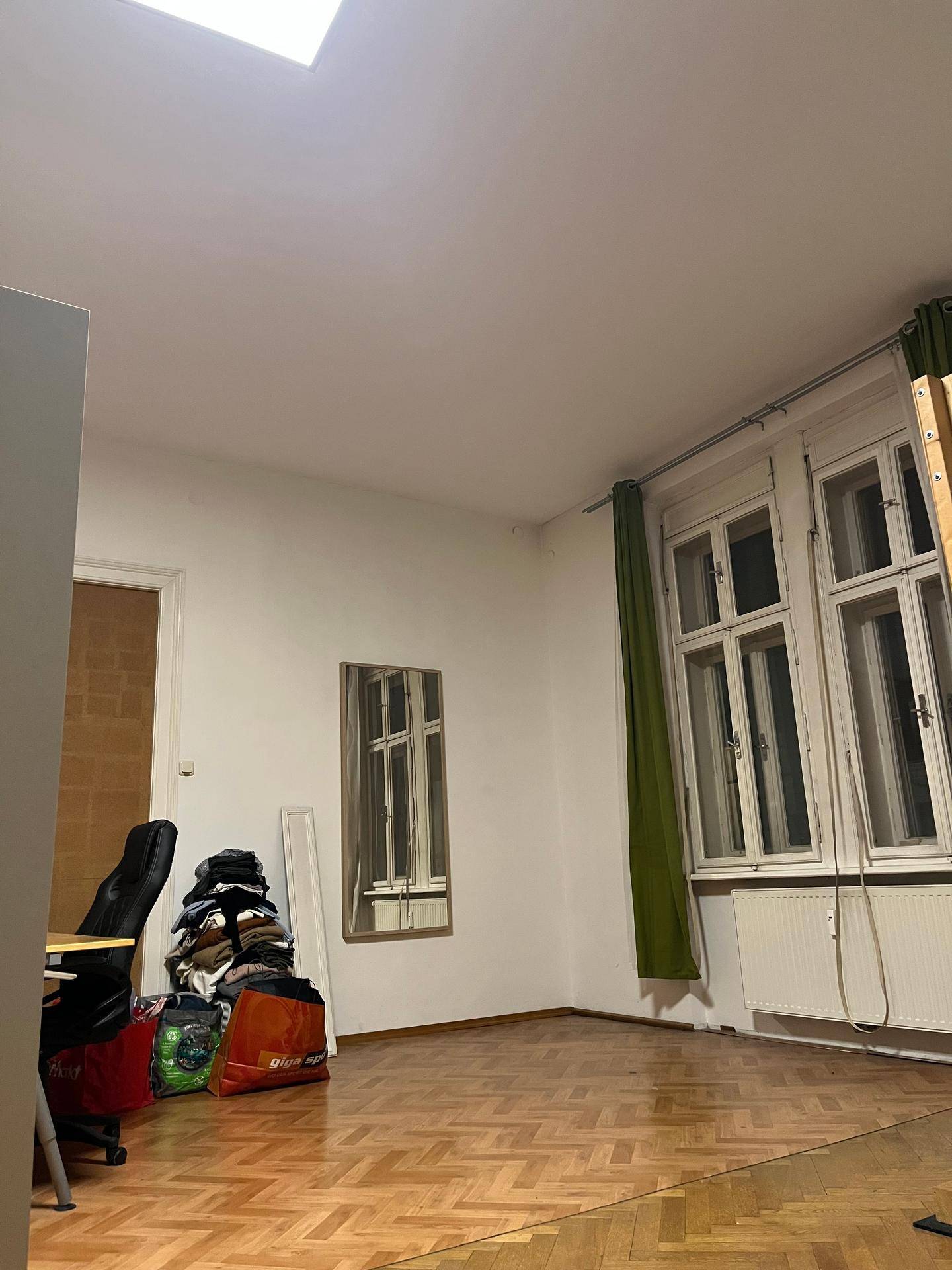 Heller Raum mit Parkettboden, großen Fenstern und einem Schreibtischbereich.