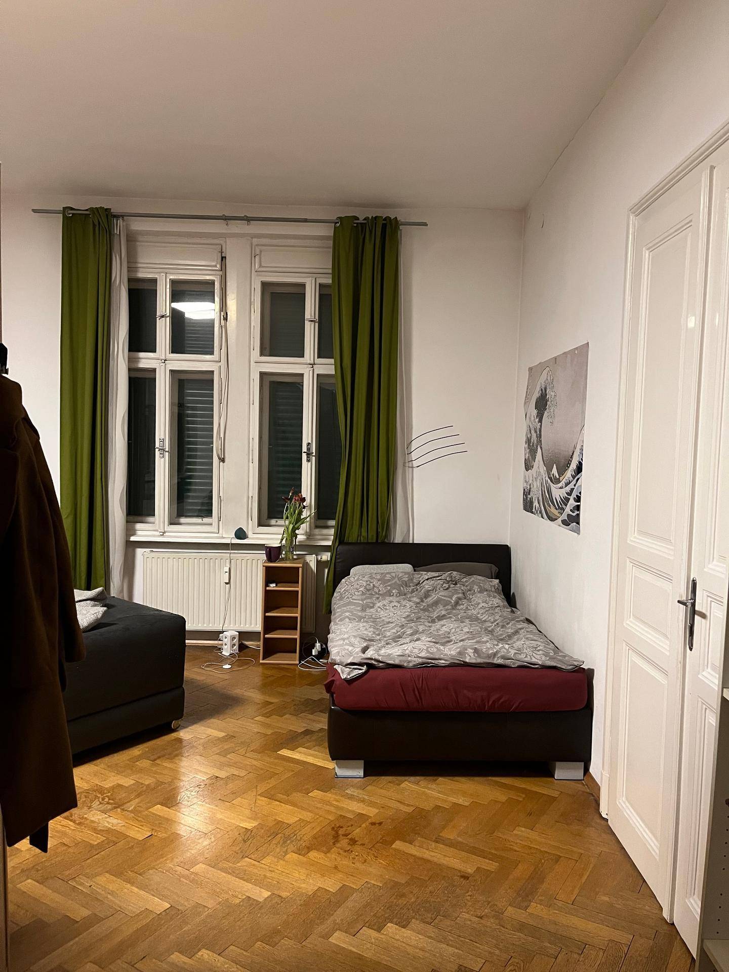 Schlafbereich mit Einzelbett, Parkettboden und einem Bild an der Wand.