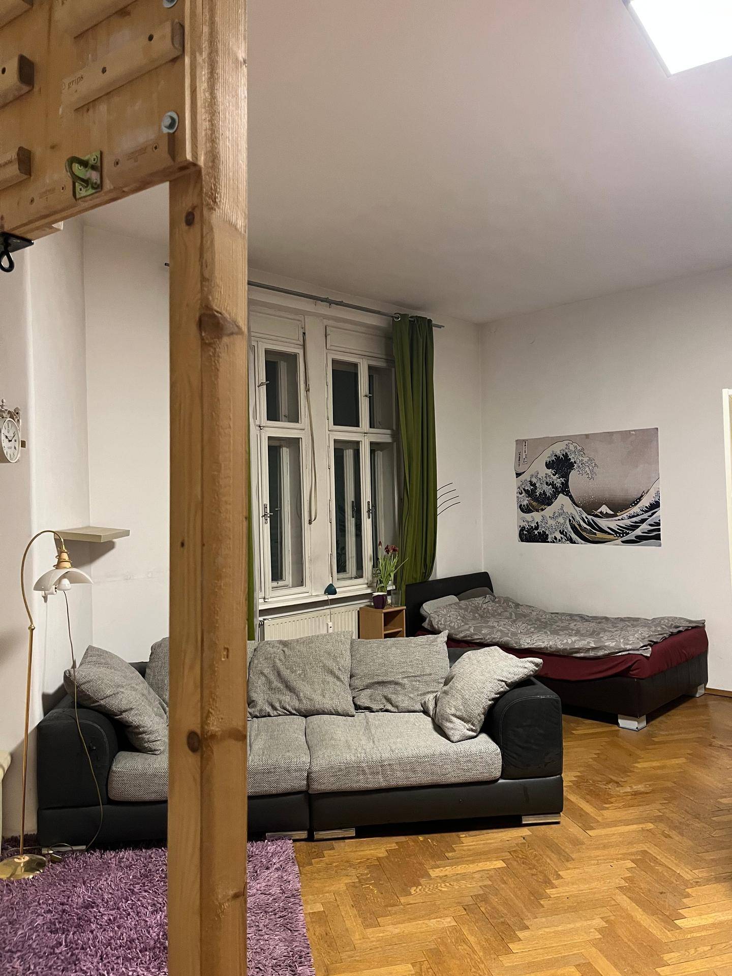 Kombinierter Wohn- und Schlafbereich mit Sofas, Einzelbett und Parkettboden.