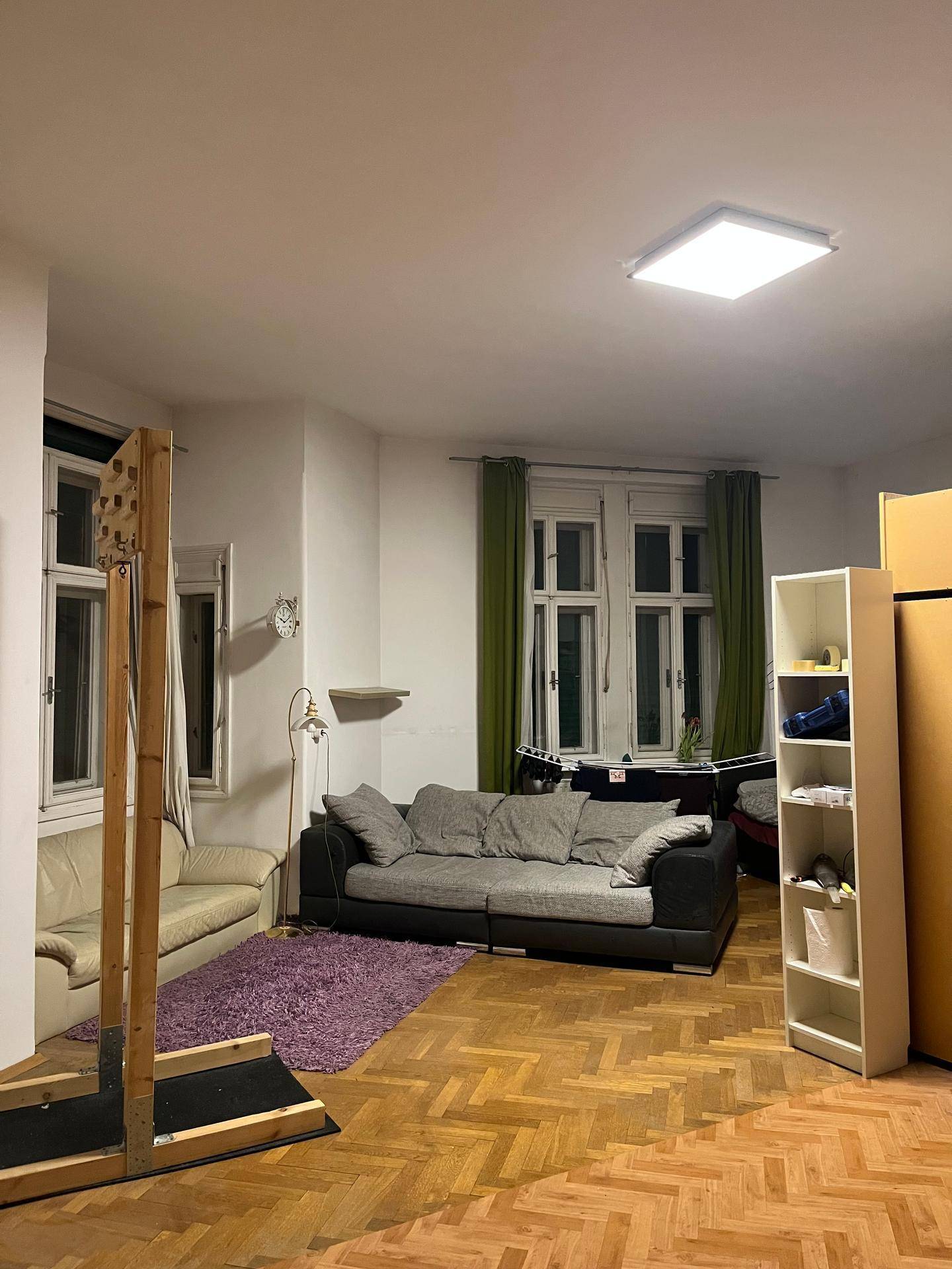 Geräumiges Wohnzimmer mit Parkettboden, zwei Sofas und einem Einzelbett.