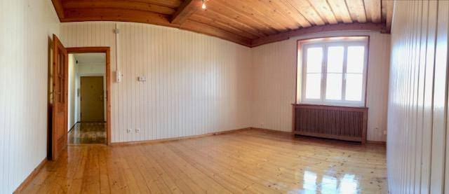 Geräumiger Raum mit Holzvertäfelung, Holzboden und einem Fenster, das viel Licht hereinlässt.
