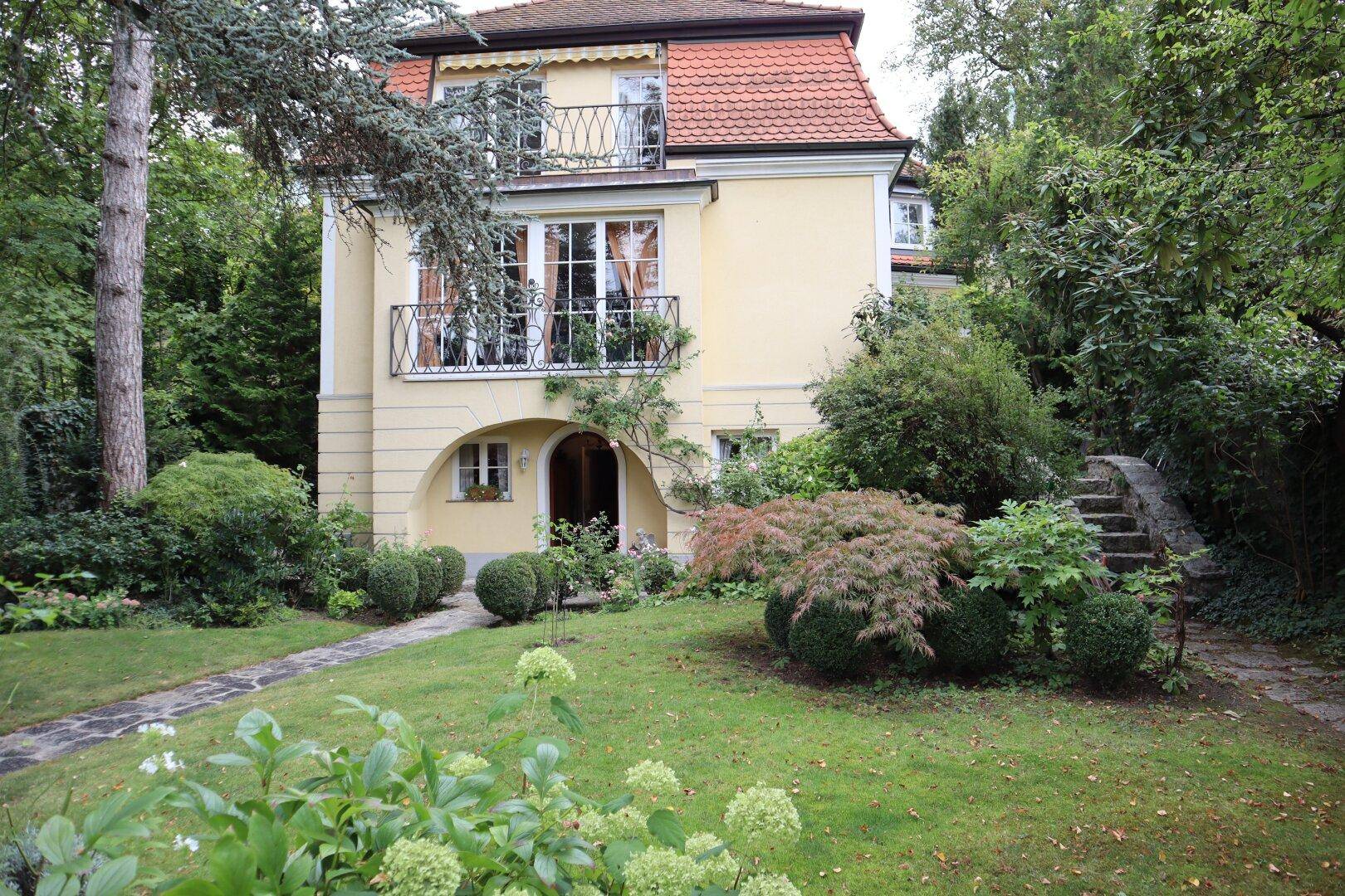 Historisches Haus mit üppigem Garten und Steintreppe im Grünen.