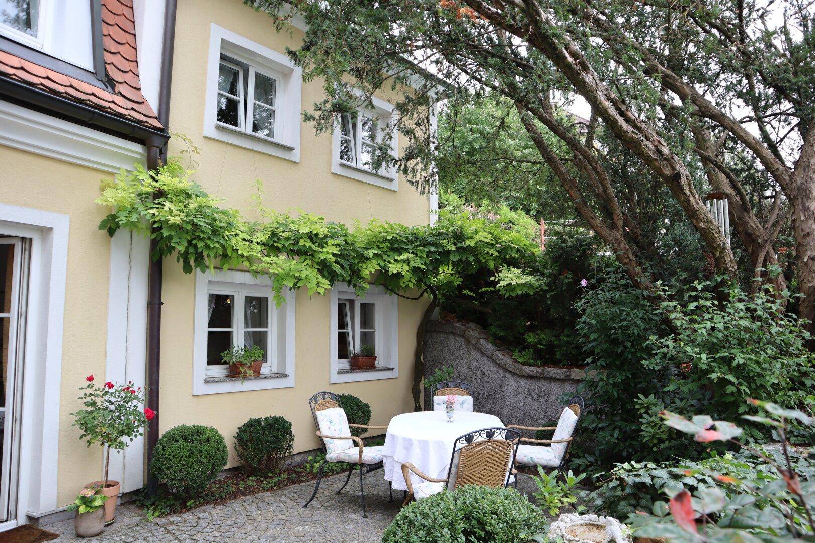 Gemütliche Terrasse mit Sitzgelegenheiten und Kletterpflanzen am Haus.