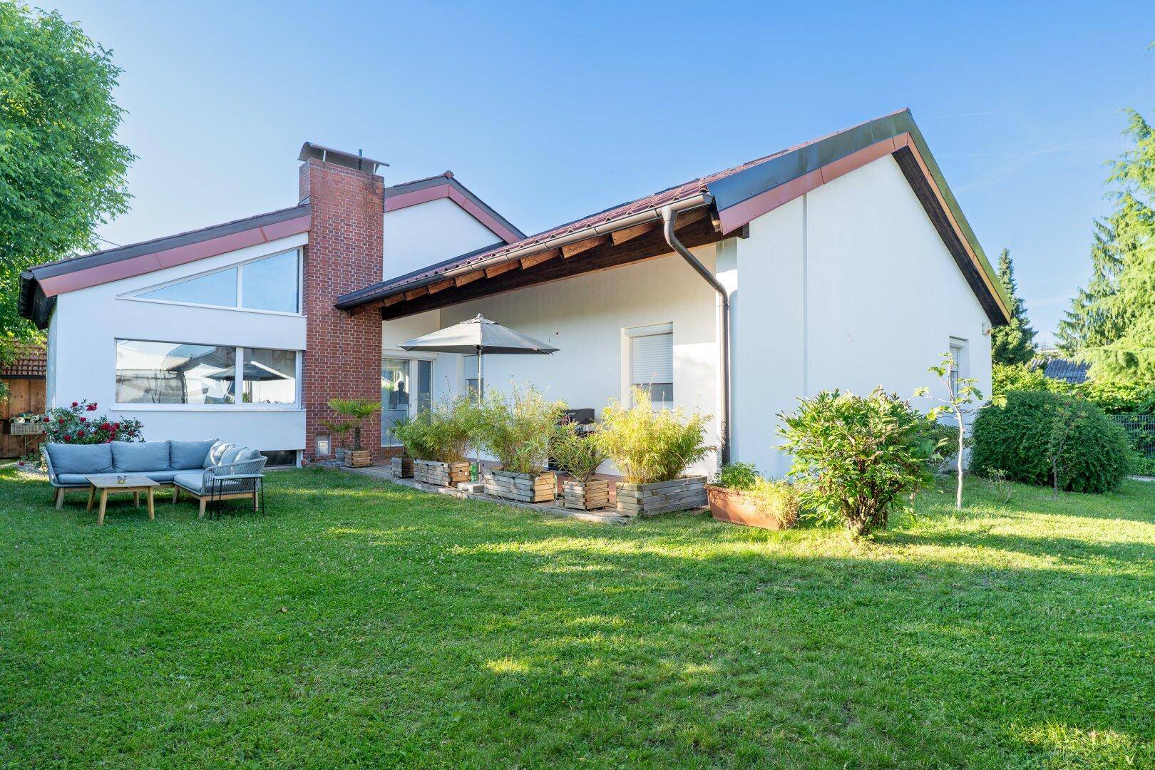 Weitläufiger Gartenbereich neben dem Haus mit gepflegtem Rasen und einer einladenden Lounge-Ecke.