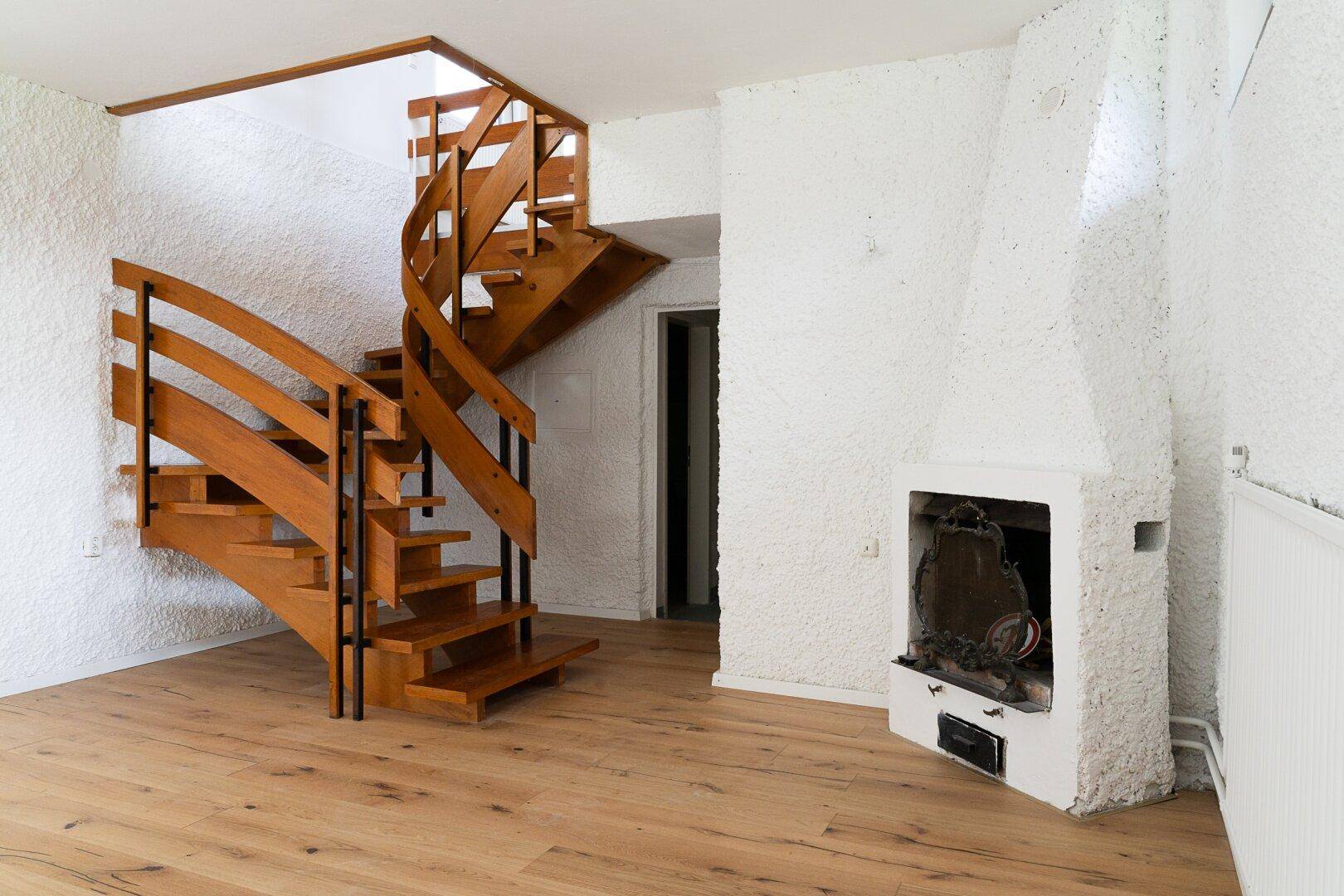 Geräumiger Kellerraum mit Holztreppe und Kamin, ideal für Lagerung oder Ausbau.