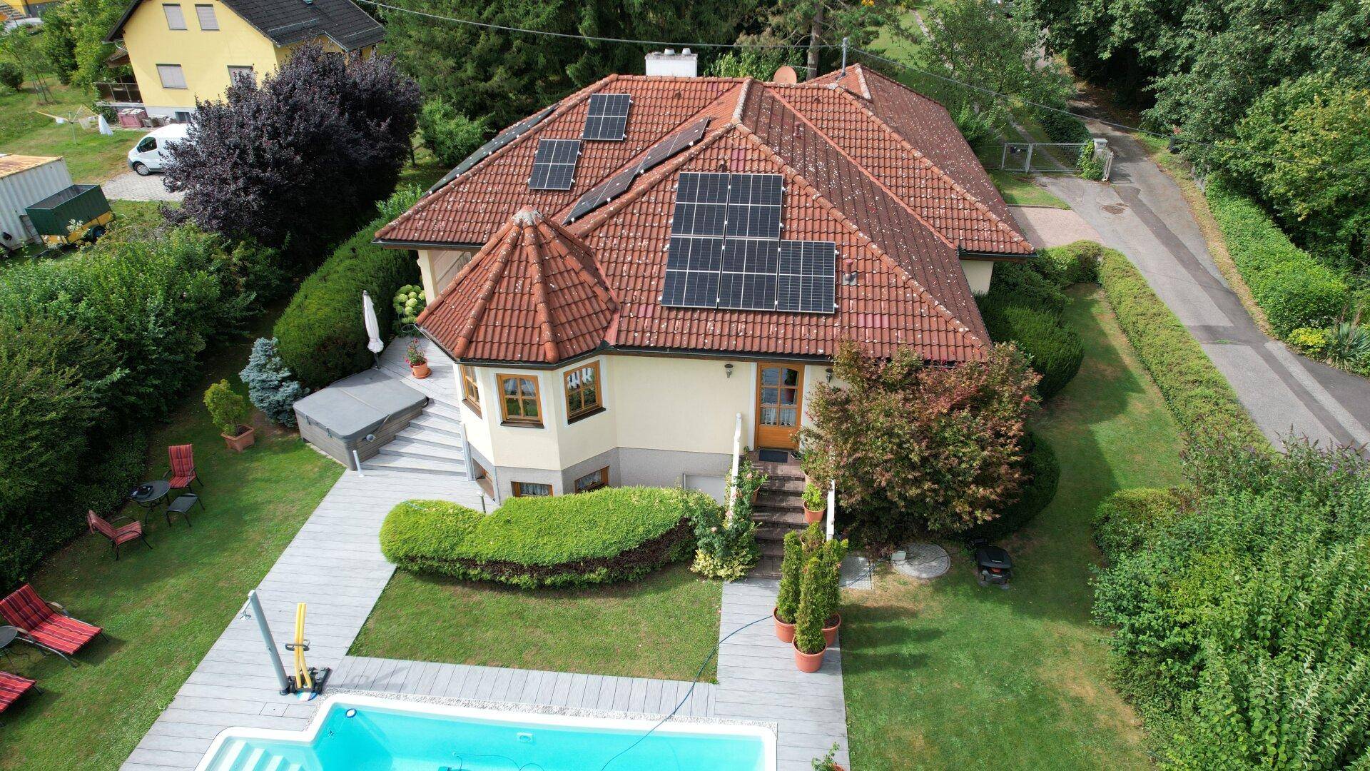 Luftaufnahme des Hauses mit Poolbereich, großem Garten und Photovoltaikanlage auf dem Dach.