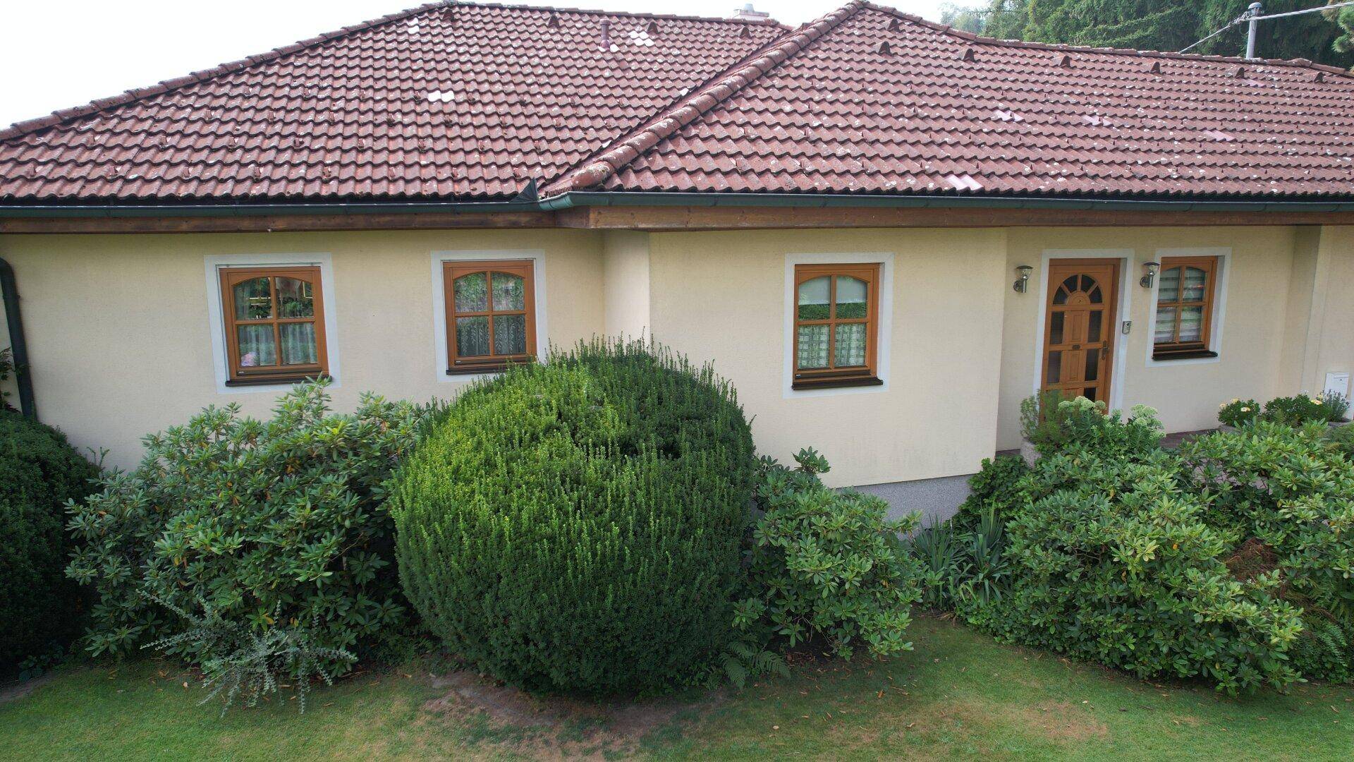 Fassade des Hauses mit gepflegten Büschen, Holzfenstern und traditionellem Ziegeldach.