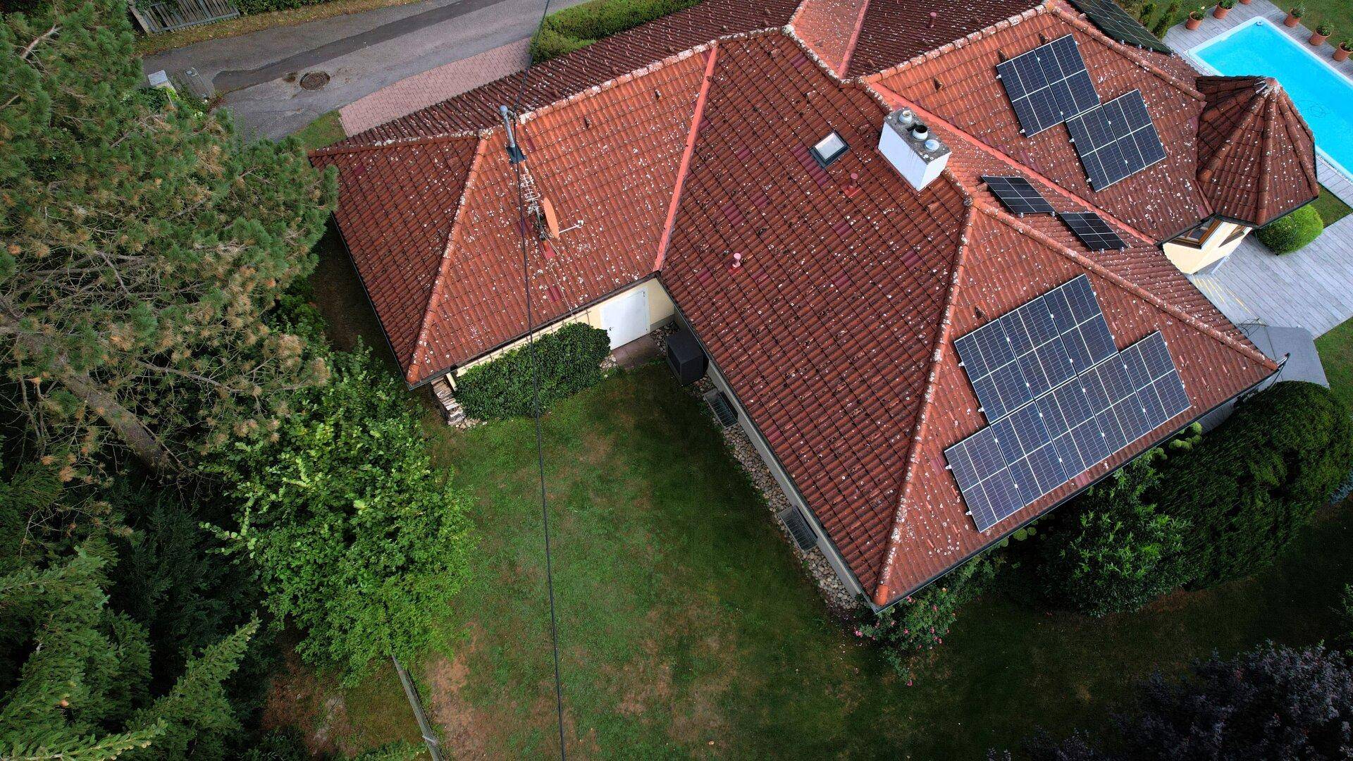 Dachansicht des Hauses mit mehreren Photovoltaikmodulen und traditionellen Ziegeln.