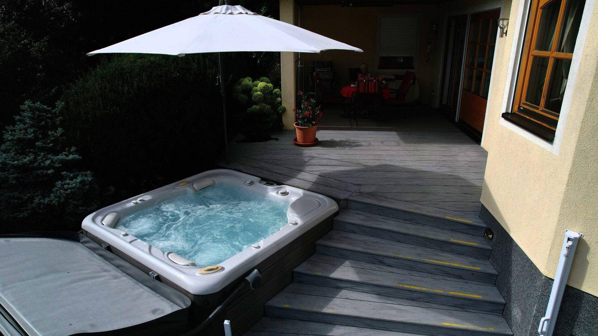 Entspannungsbereich auf der Terrasse mit sprudelndem Whirlpool und Sonnenschirm.