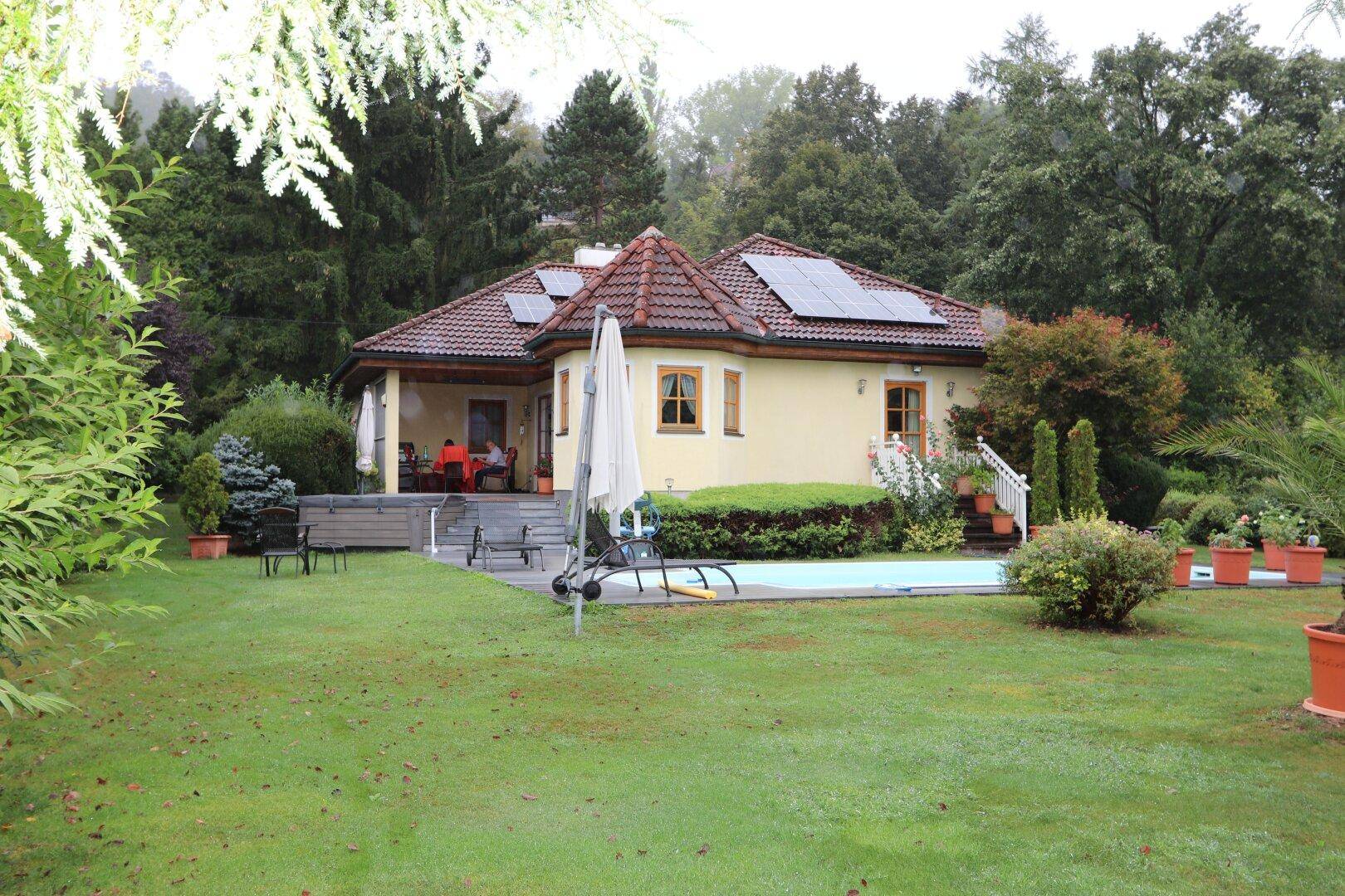 Charmantes Haus umgeben von einem weitläufigen Garten mit Pool und üppiger Vegetation.
