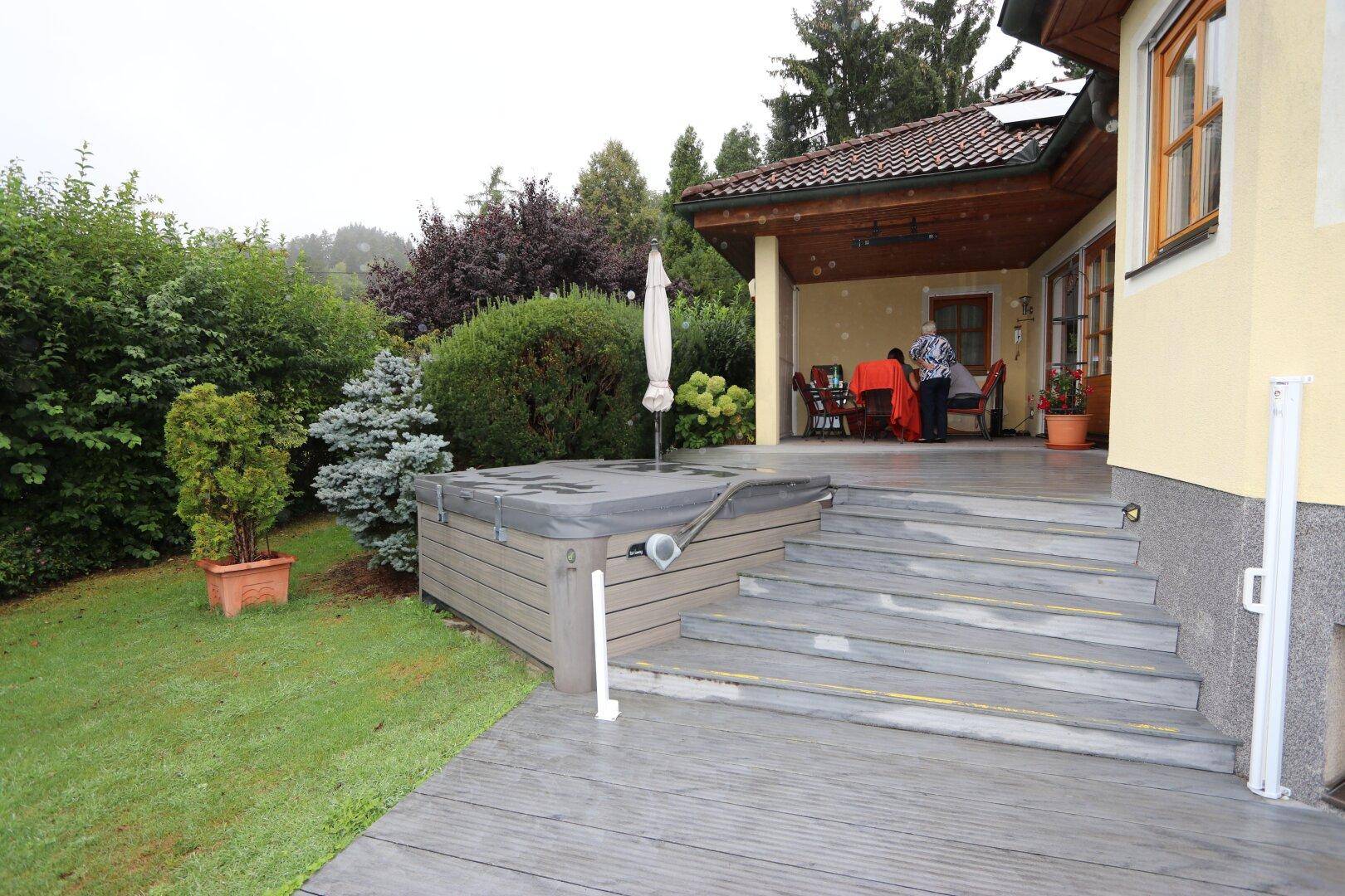 Überdachte Terrasse mit integriertem Whirlpool und gemütlichem Essbereich im Freien.