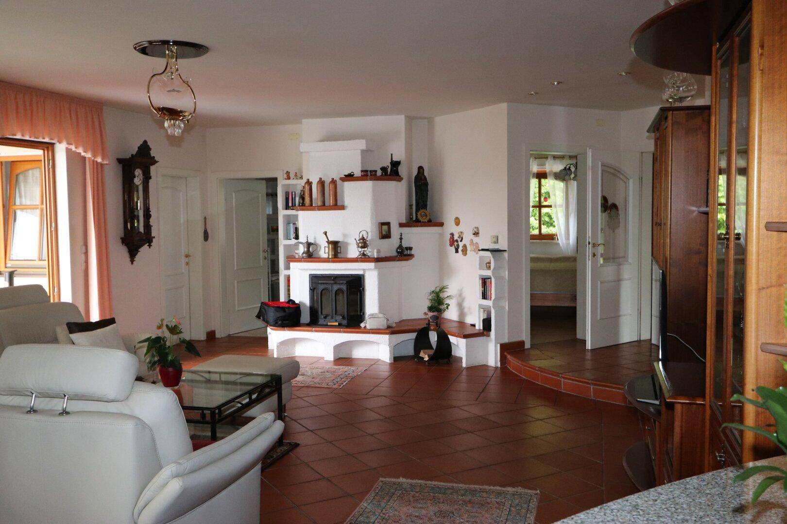 Helles Wohnzimmer mit traditionellem Kamin, Terrakottaboden und bequemen Sofas.