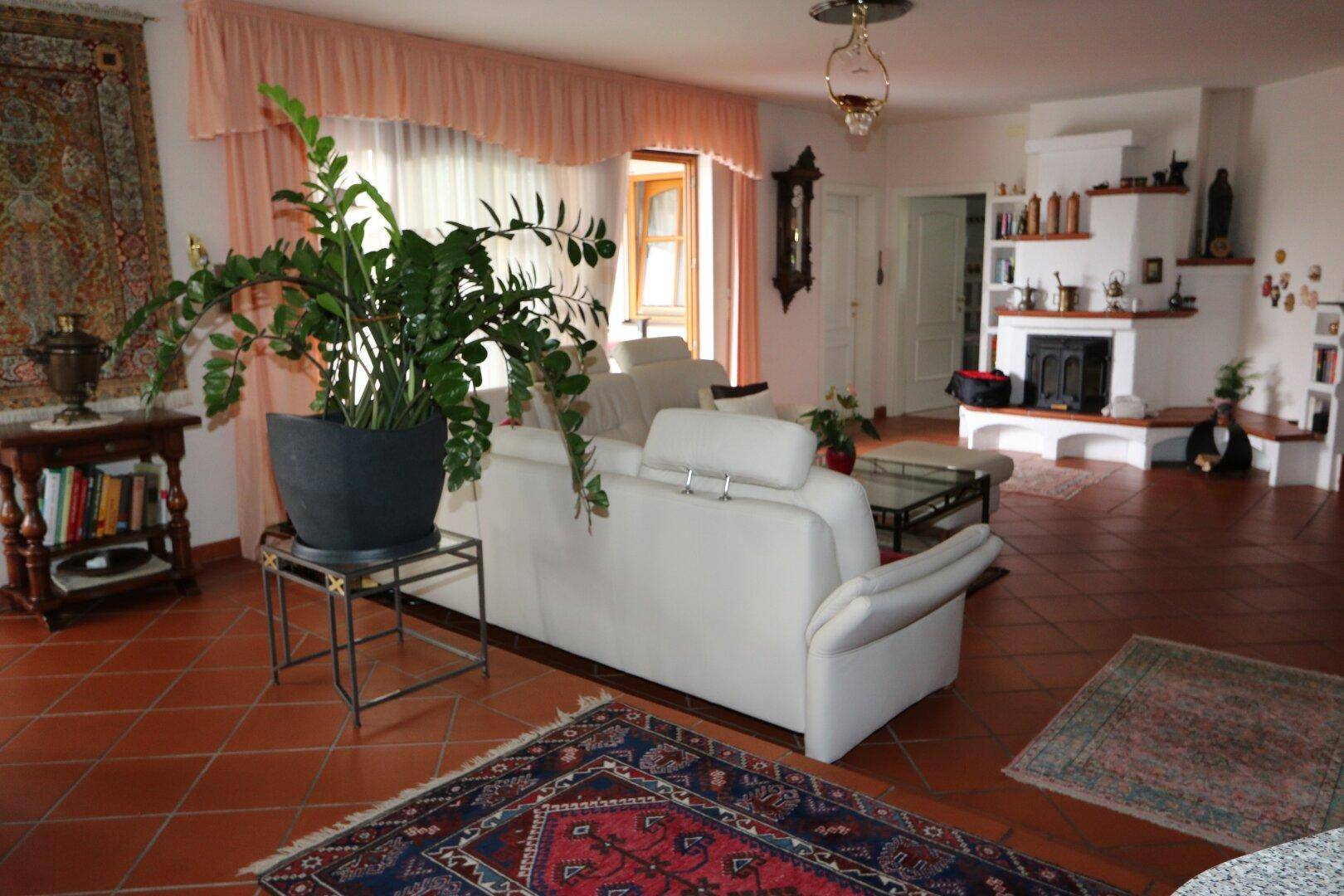 Geräumiges Wohnzimmer mit gemütlichem Sofa, Kamin und traditionellem Terrakottaboden.