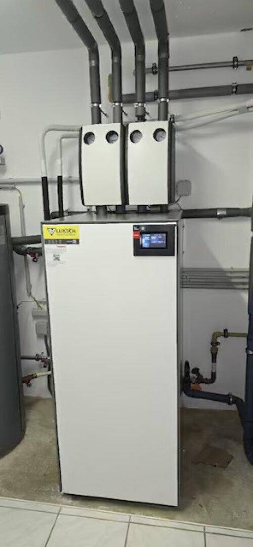 Moderne Heizungsanlage mit Wärmepumpe und zugehörigen Rohrleitungen in einem Technikraum.