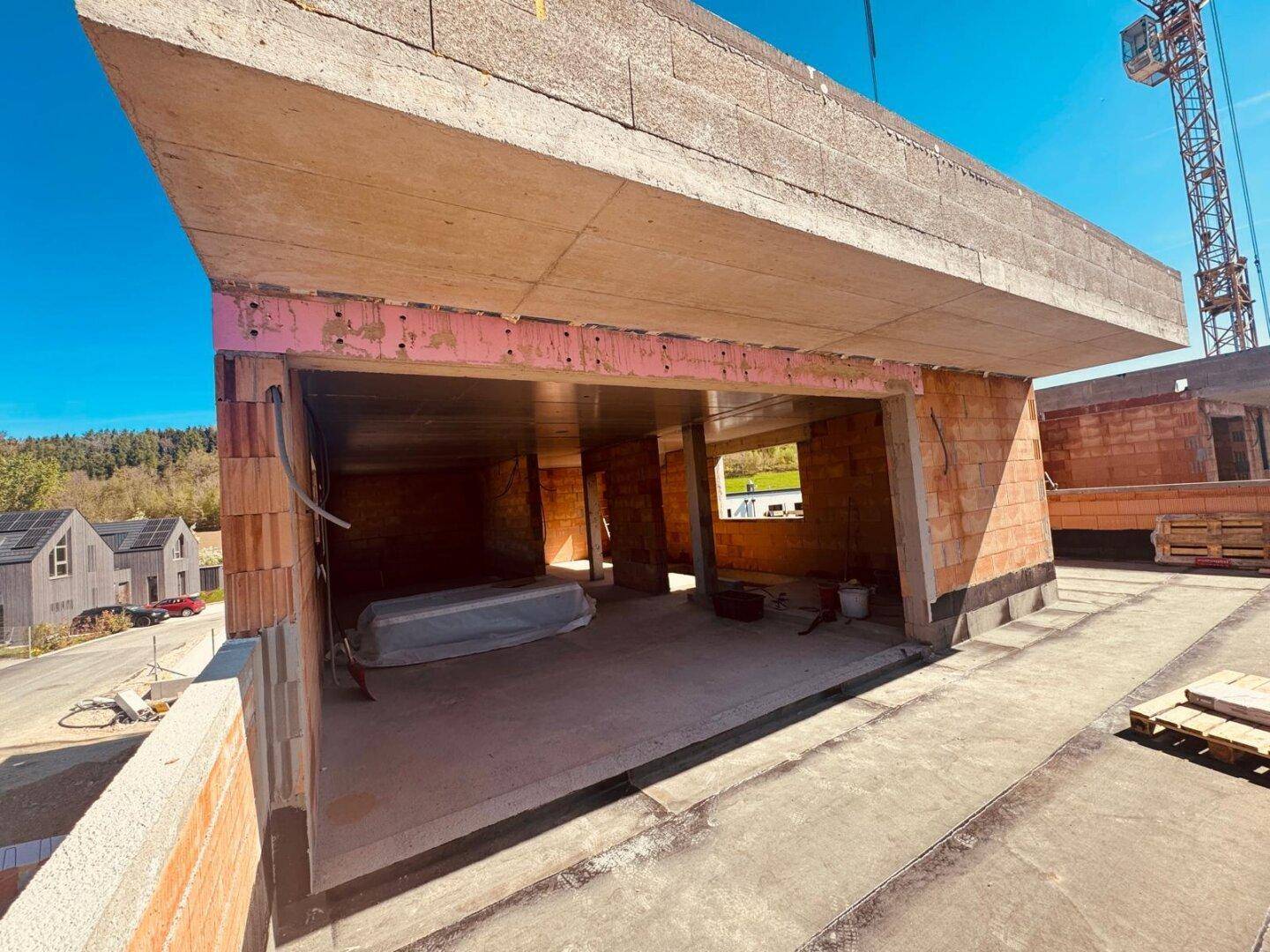 Innenansicht eines Rohbaus mit Betonwänden und -decken, bereit für den Ausbau.