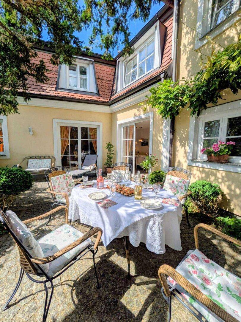 Sonnige Terrasse mit gedecktem Tisch und Zugang zu den Innenräumen des charmanten Gebäudes.