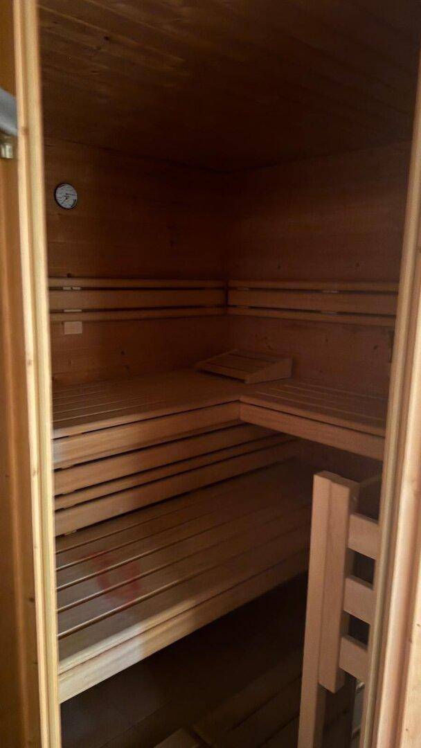 Holzvertäfelte Sauna mit mehreren Sitzebenen für Entspannung und Wellness im Haus.