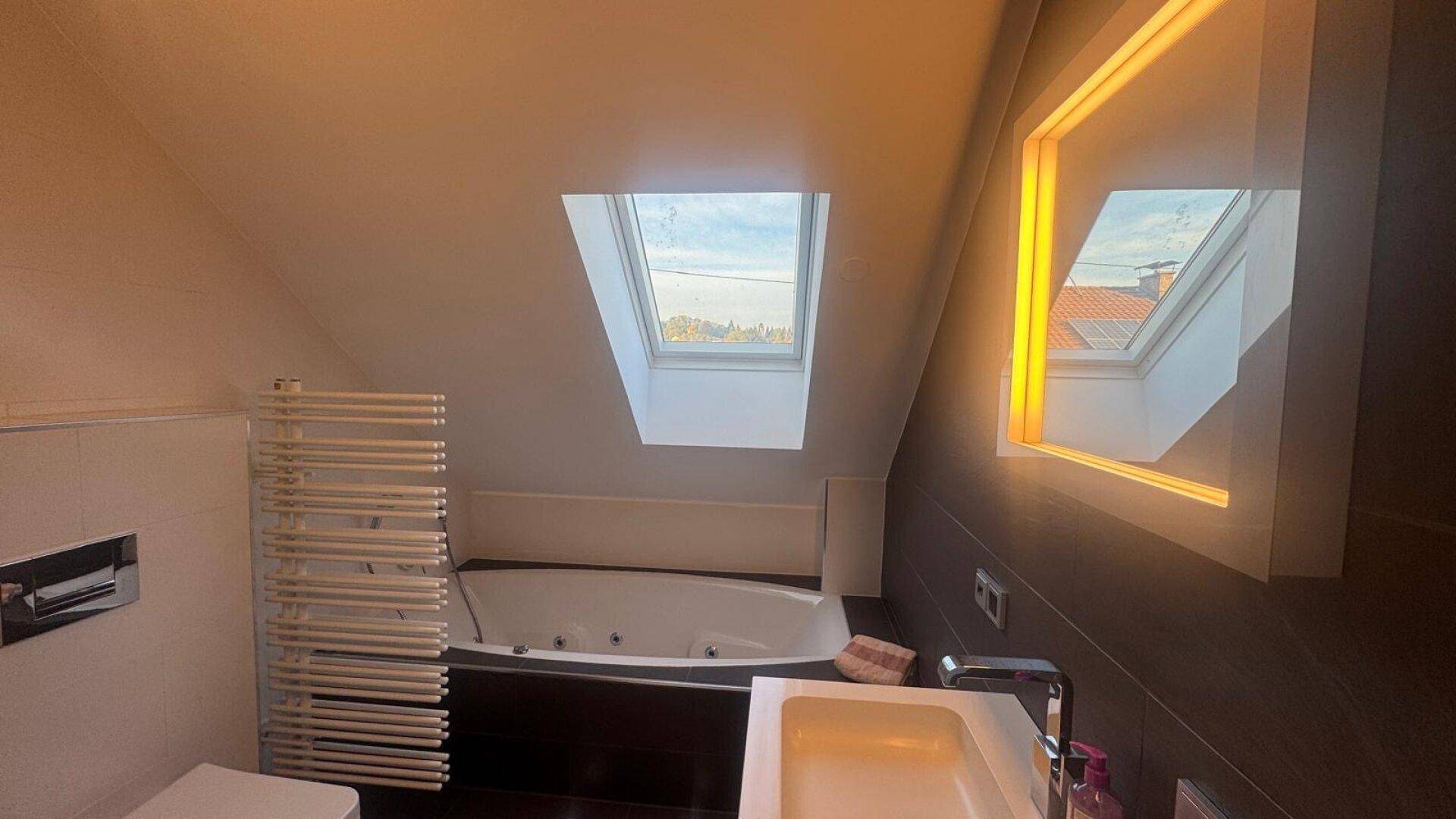 Helles Dachgeschoss-Badezimmer mit Whirlpool, Dachfenstern und modernem Waschtisch.