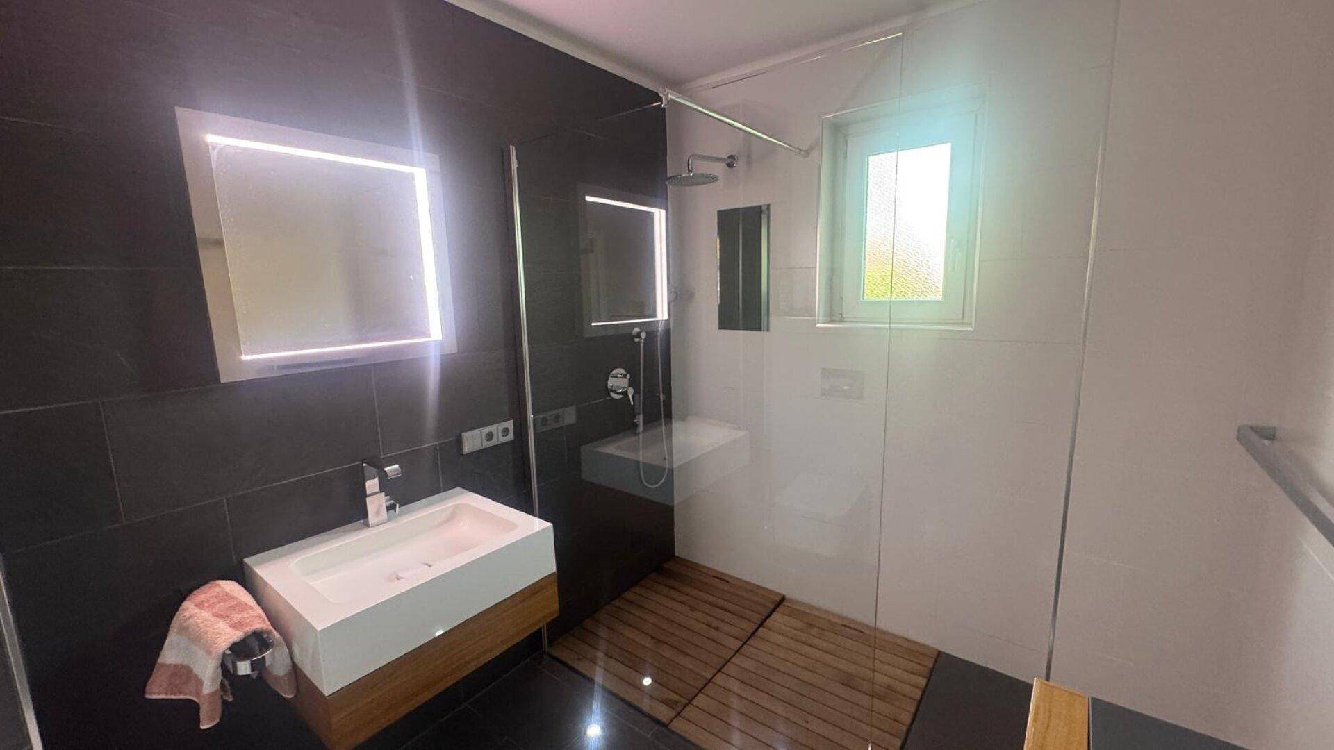 Helles Badezimmer mit begehbarer Dusche, modernem Waschtisch und Fenster für Tageslicht.