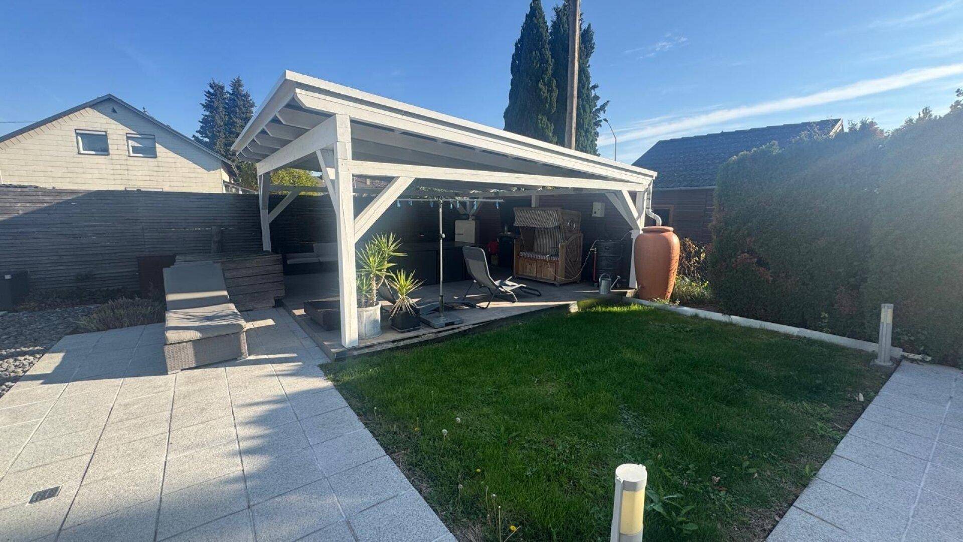 Gemütliche Terrasse mit Pergola, Sitzgelegenheiten und angrenzendem Rasenbereich für Entspannung.