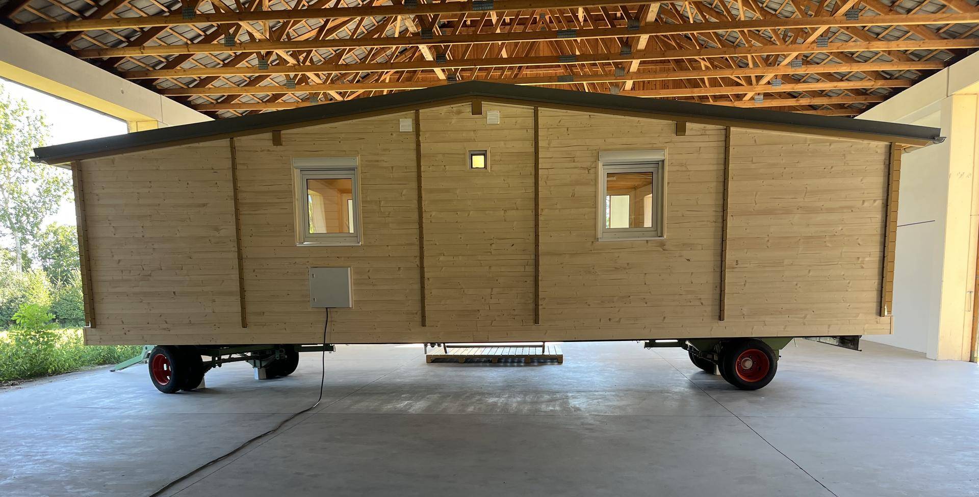 Rückseite des Tiny Houses mit Holzfassade und kleinen Fenstern unter einem schützenden Dach.