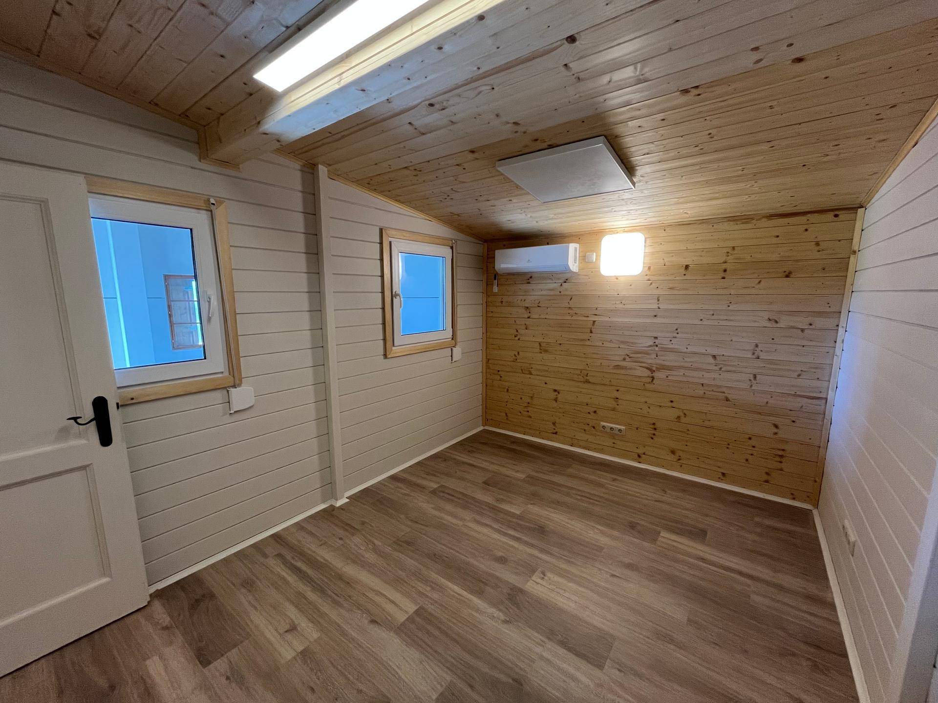 Heller Innenraum mit Holzverkleidung an Wänden und Decke sowie modernem Laminatboden.