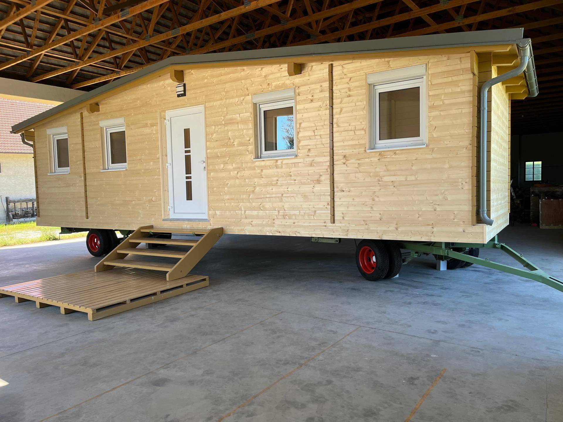 Seitenansicht des Tiny Houses mit Holzverkleidung, Eingangsbereich und mobiler Bauweise auf Rädern.
