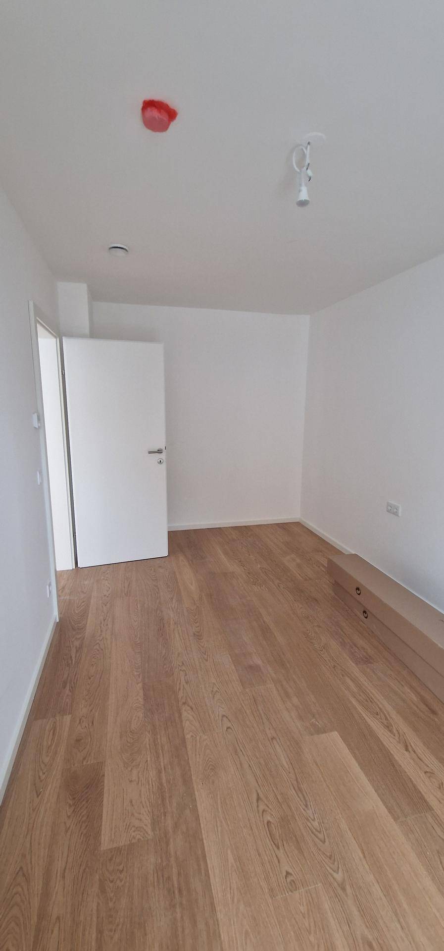 Heller, leerer Raum mit Holzboden und weißen Wänden, bereit zur individuellen Gestaltung.