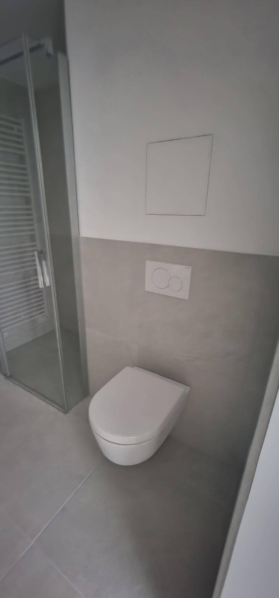 Modernes WC mit wandhängender Toilette und Duschkabine, ausgestattet mit grauen Fliesen.