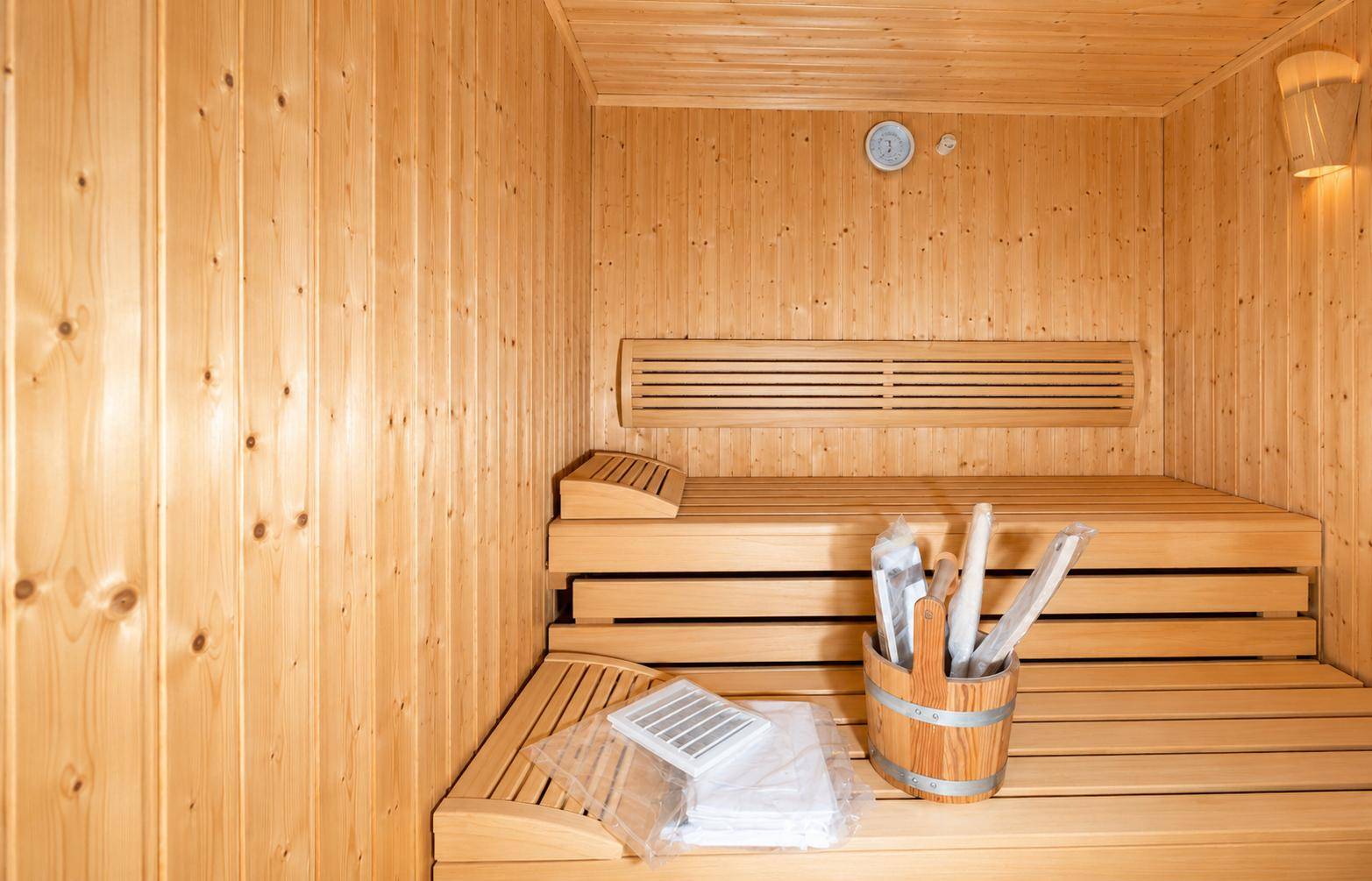Traditionelle Holzsauna mit bequemen Bänken und Zubehör für entspannende Wellness-Momente.