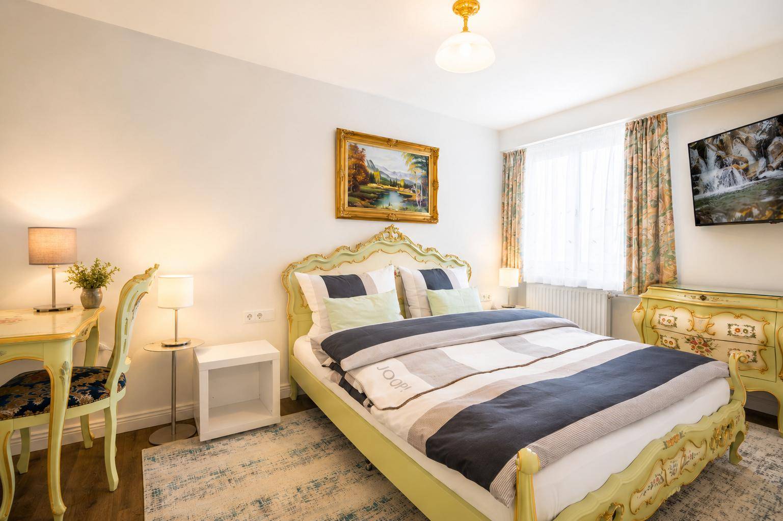 Klassisches Schlafzimmer mit opulentem Bettrahmen, Holzboden und Blick nach draußen.