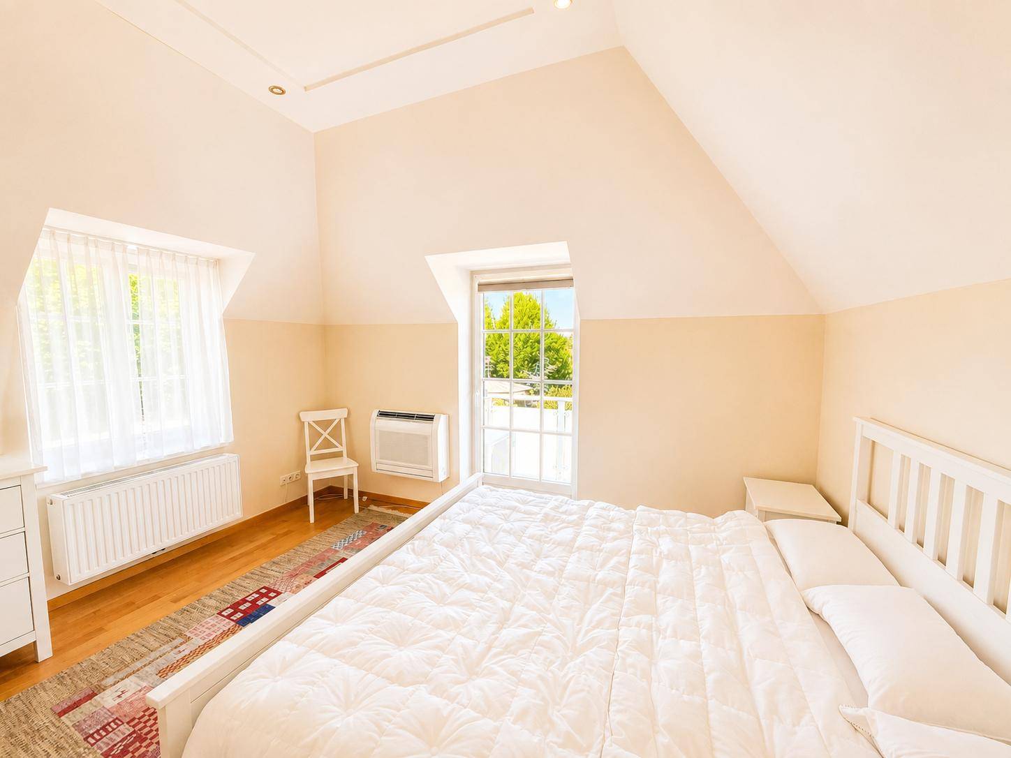 Gemütliches Schlafzimmer im Dachgeschoss mit Holzboden, Fenster und viel Tageslicht.