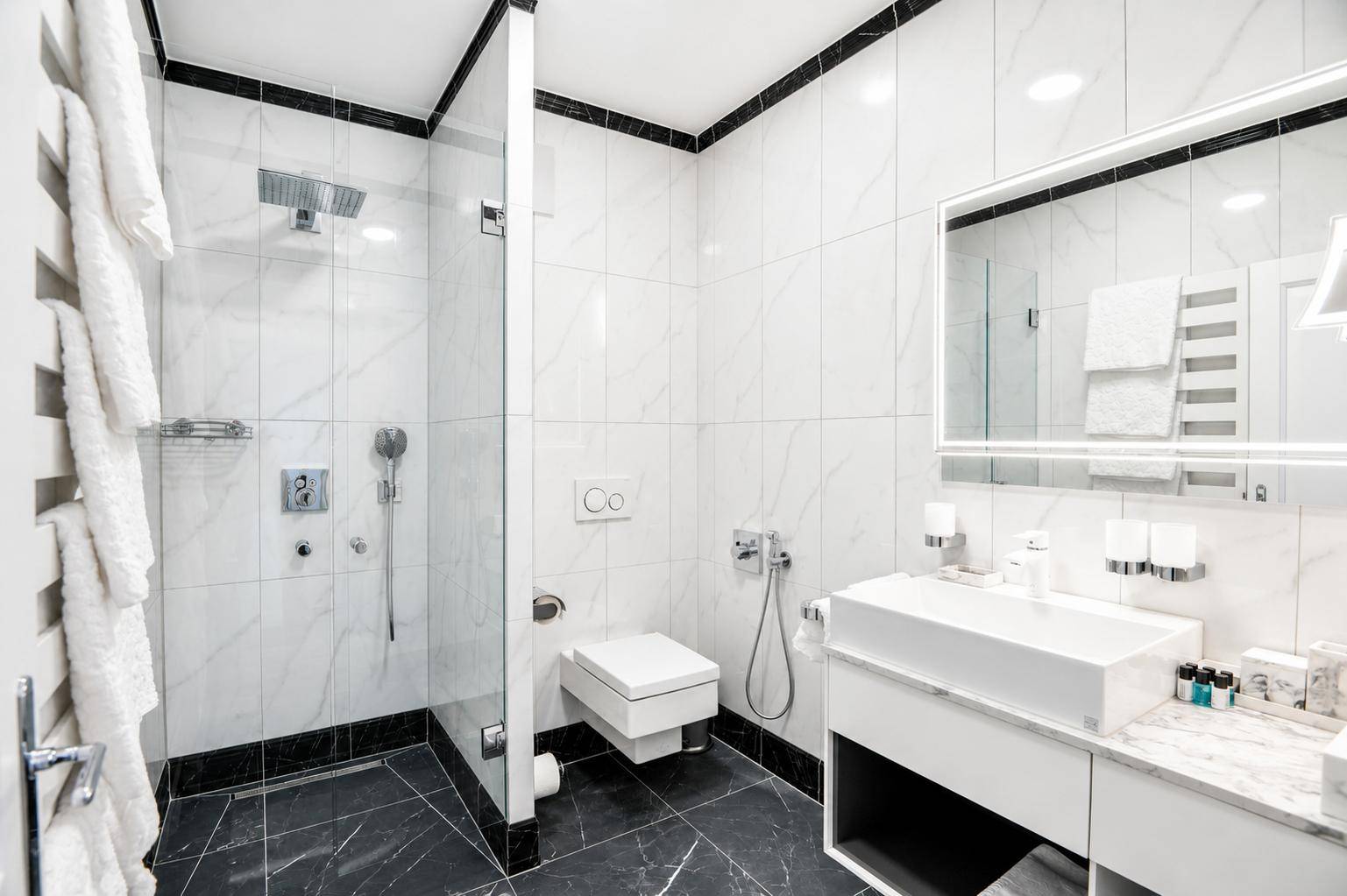Elegantes Badezimmer mit begehbarer Dusche, wandhängendem WC und stilvollen Marmorfliesen in Schwarz-Weiß.