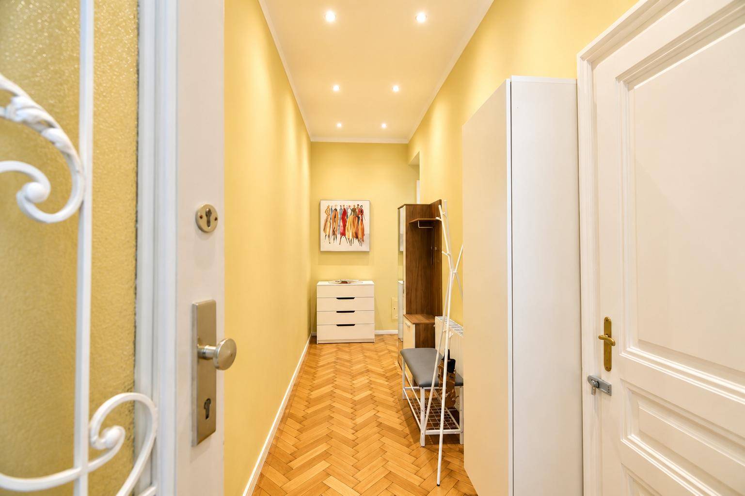 Heller Flur mit Fischgrätparkett, Einbauschrank und moderner Dekoration.