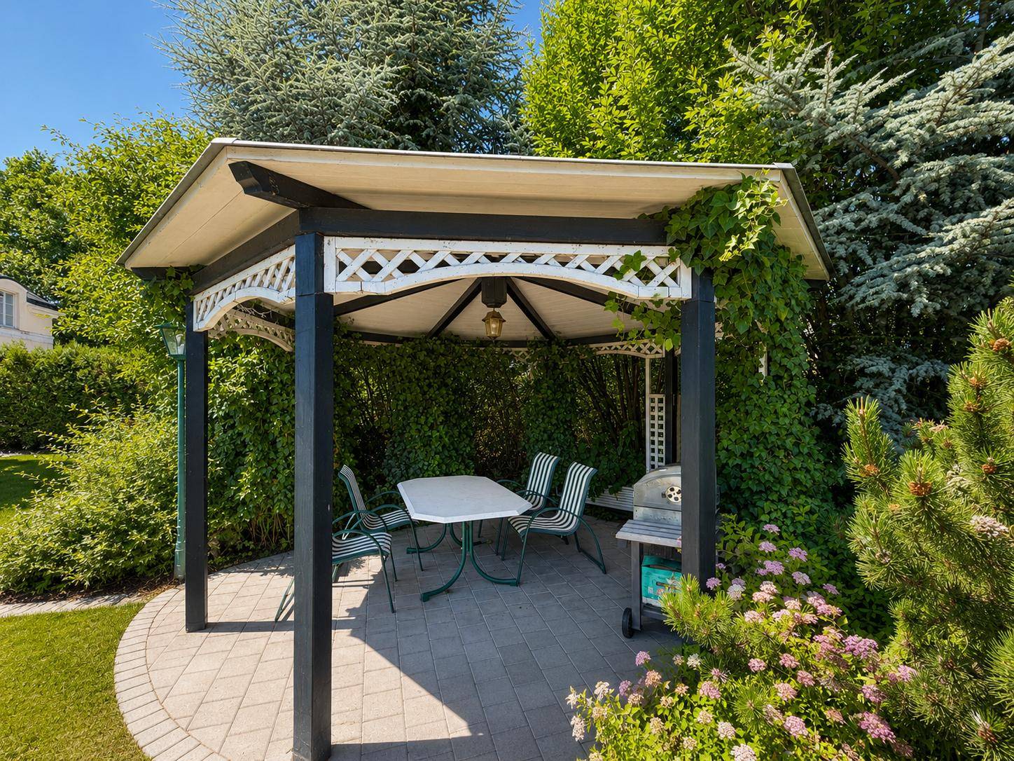 Gemütlicher Pavillon im Garten mit Sitzgelegenheiten und Grillbereich für entspannte Stunden.