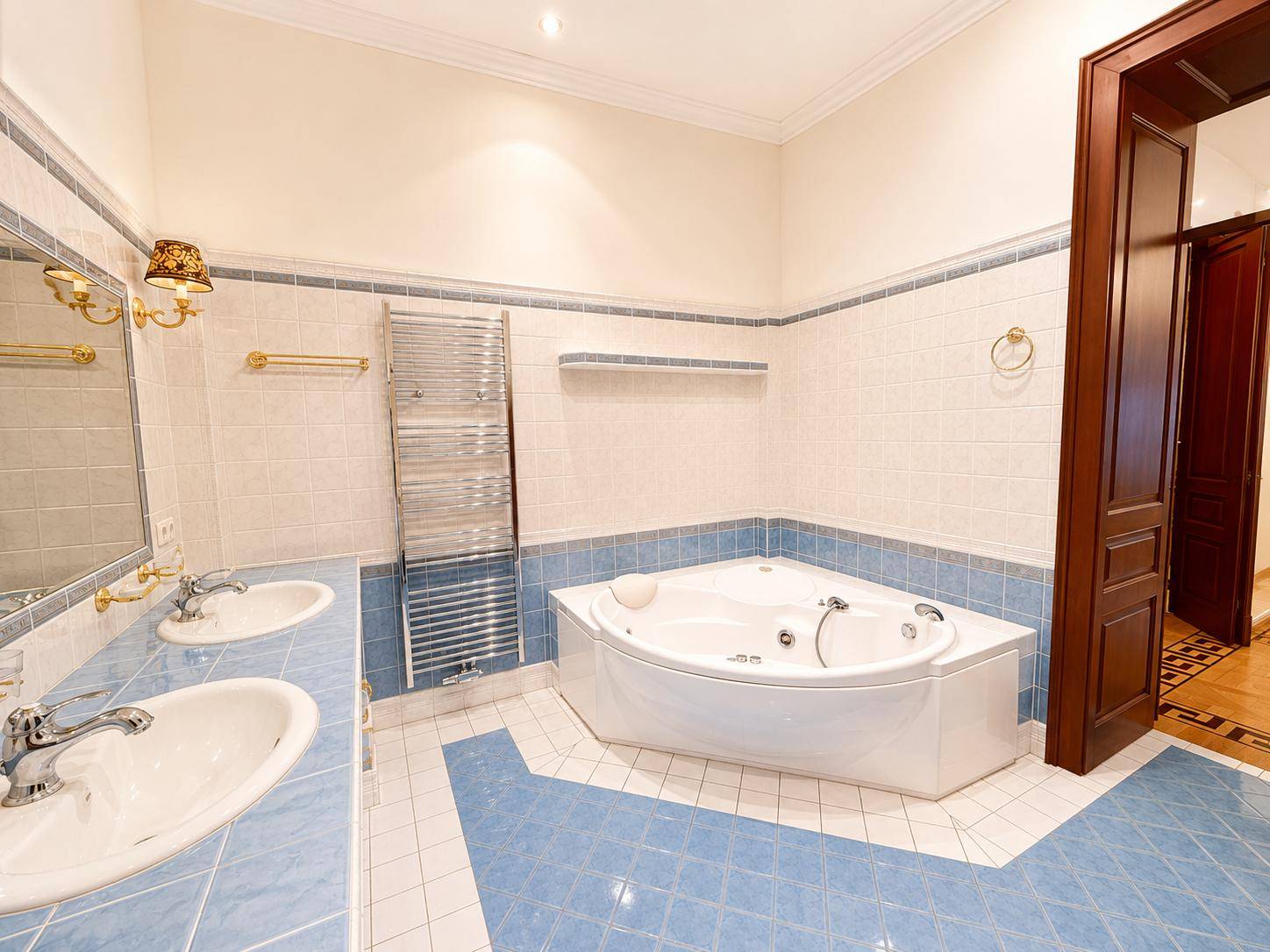 Geräumiges Badezimmer mit Eckbadewanne, doppelten Waschbecken und einem beheizten Handtuchhalter.
