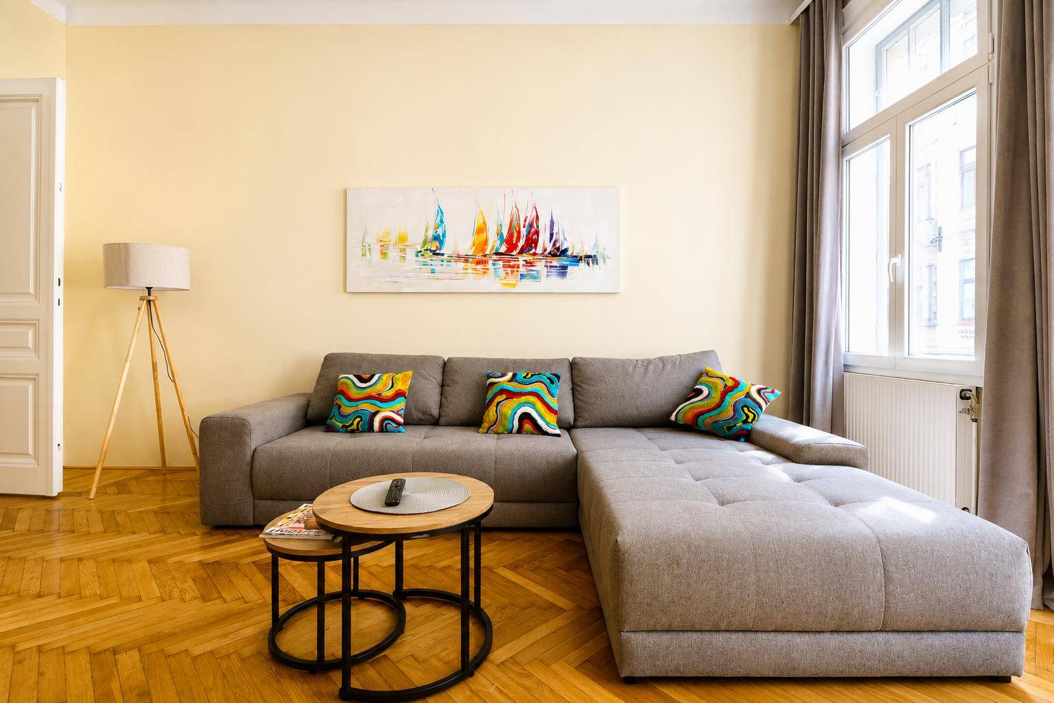 Gemütliches Wohnzimmer mit großem Ecksofa, bunten Kissen und Holzboden.